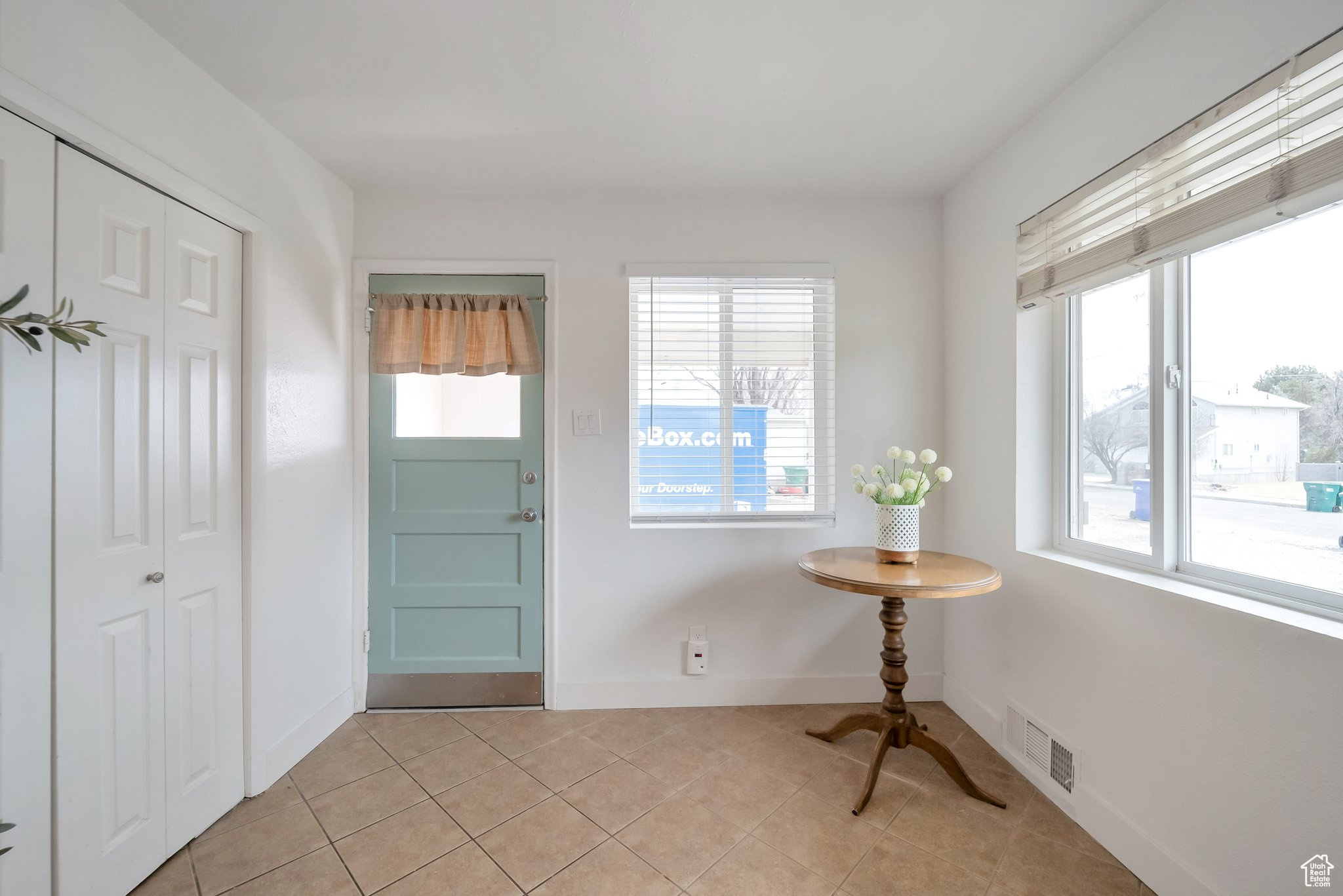 Foyer entrance with light tile patterned floors, baseboards, visible vents, and a wealth of natural light