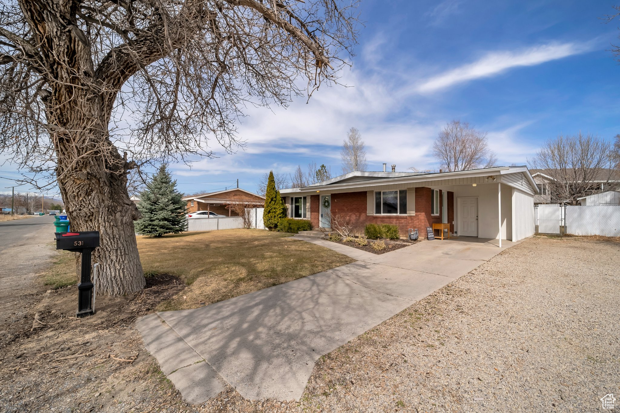 Ranch-style home with a front yard, a gate, fence, concrete driveway, and brick siding