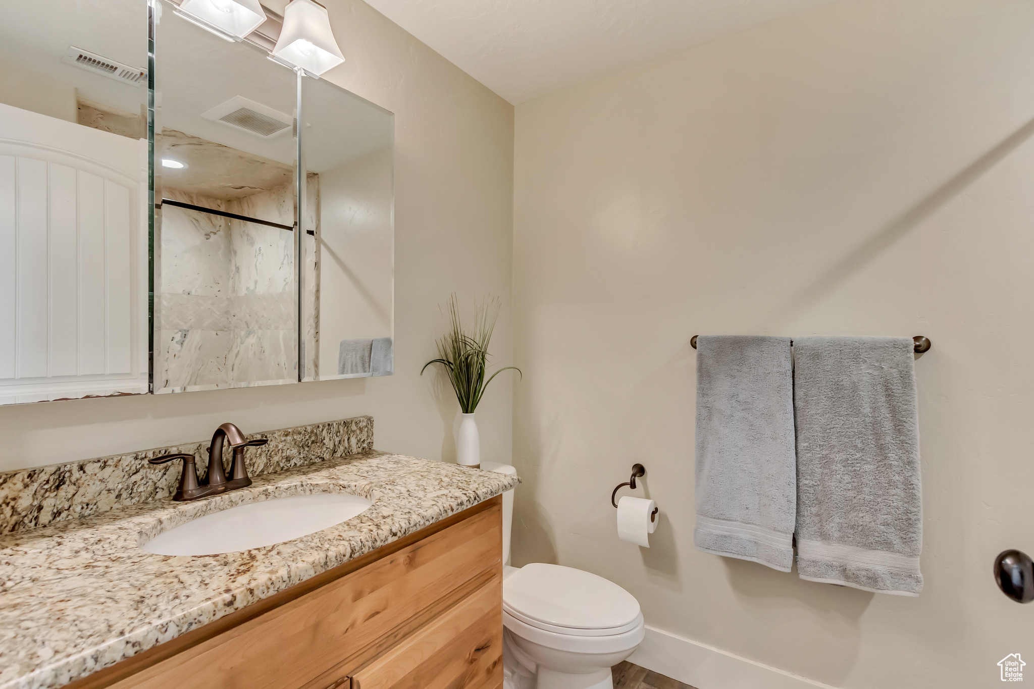 Full bathroom with vanity, baseboards, visible vents, walk in shower, and toilet