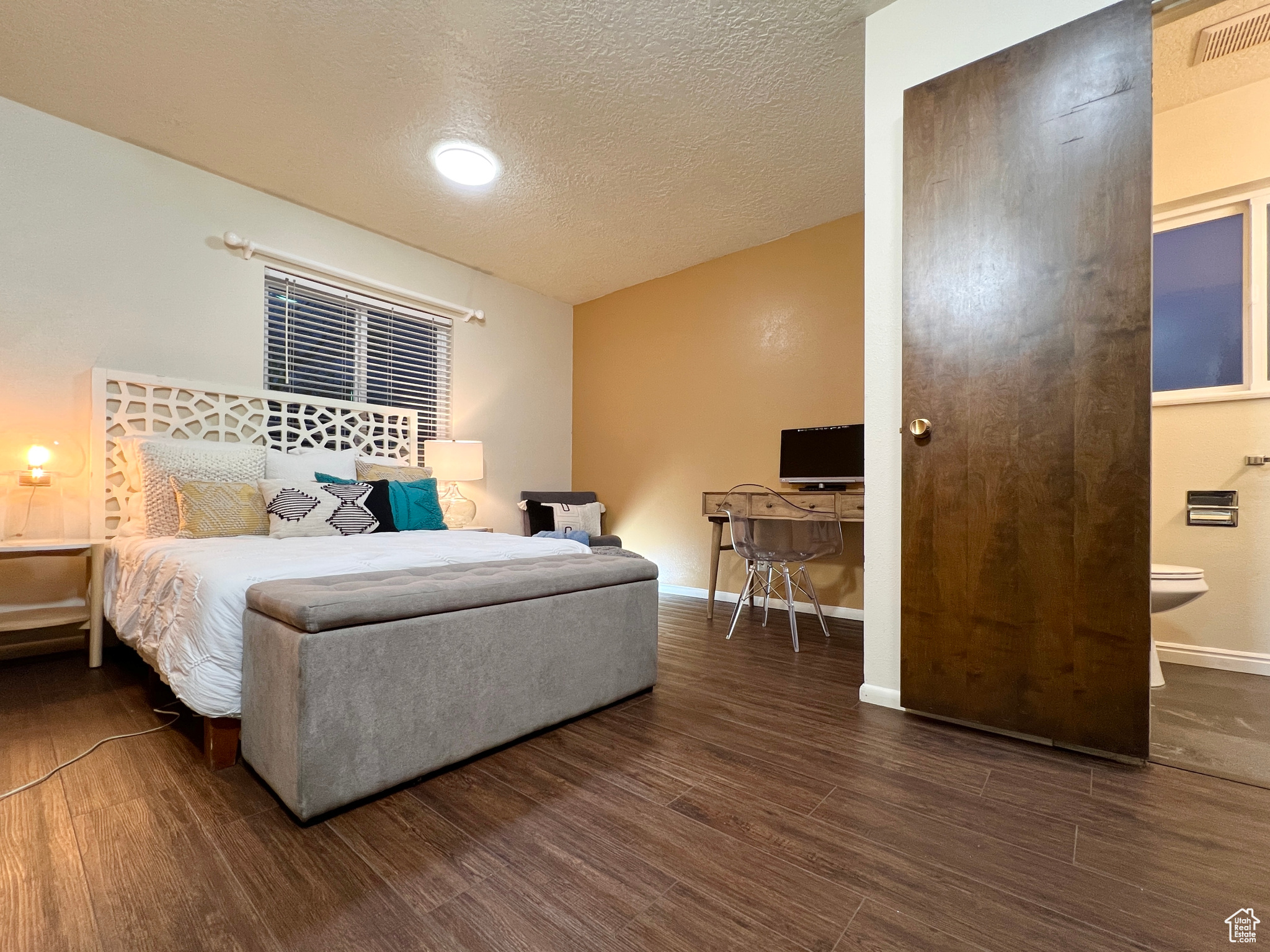 Bedroom with visible vents, baseboards, a textured ceiling, and wood finished floors