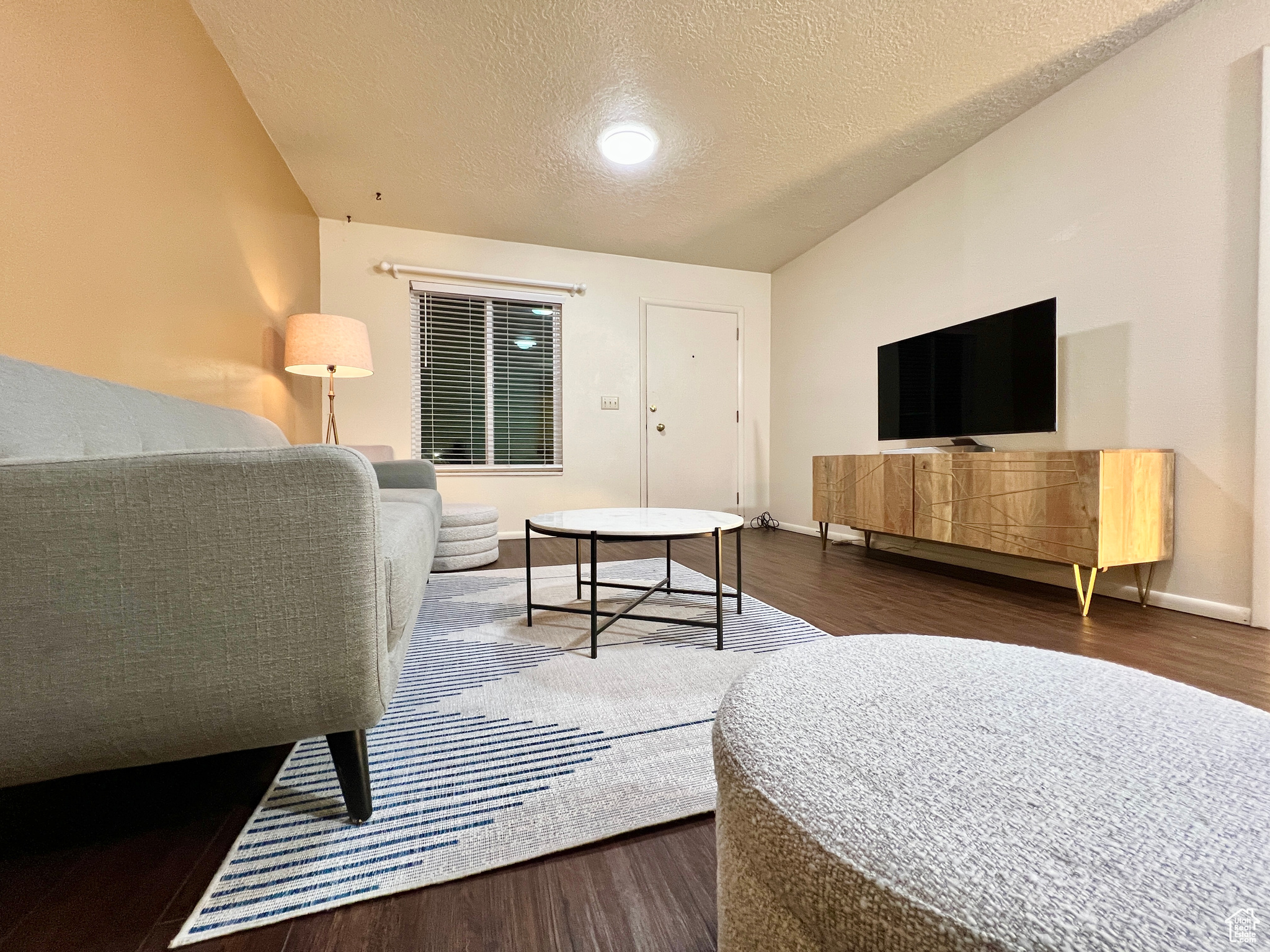 Living area featuring a textured ceiling, baseboards, and wood finished floors