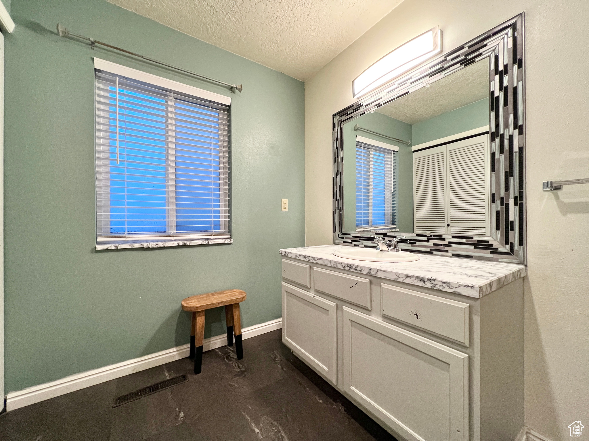 Bathroom featuring vanity, visible vents, baseboards, concrete flooring, and a textured ceiling