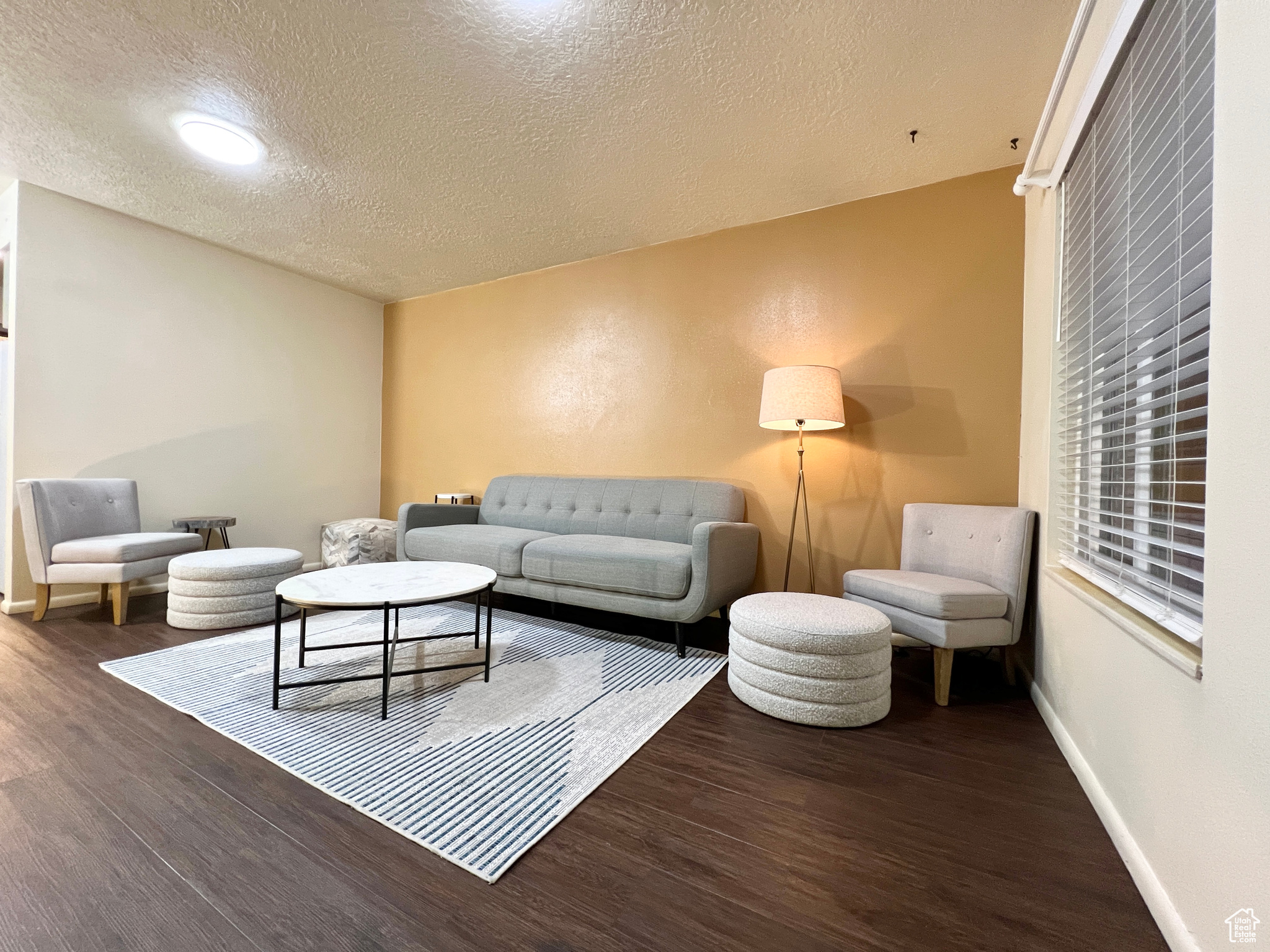 Living area featuring a textured ceiling, baseboards, and wood finished floors