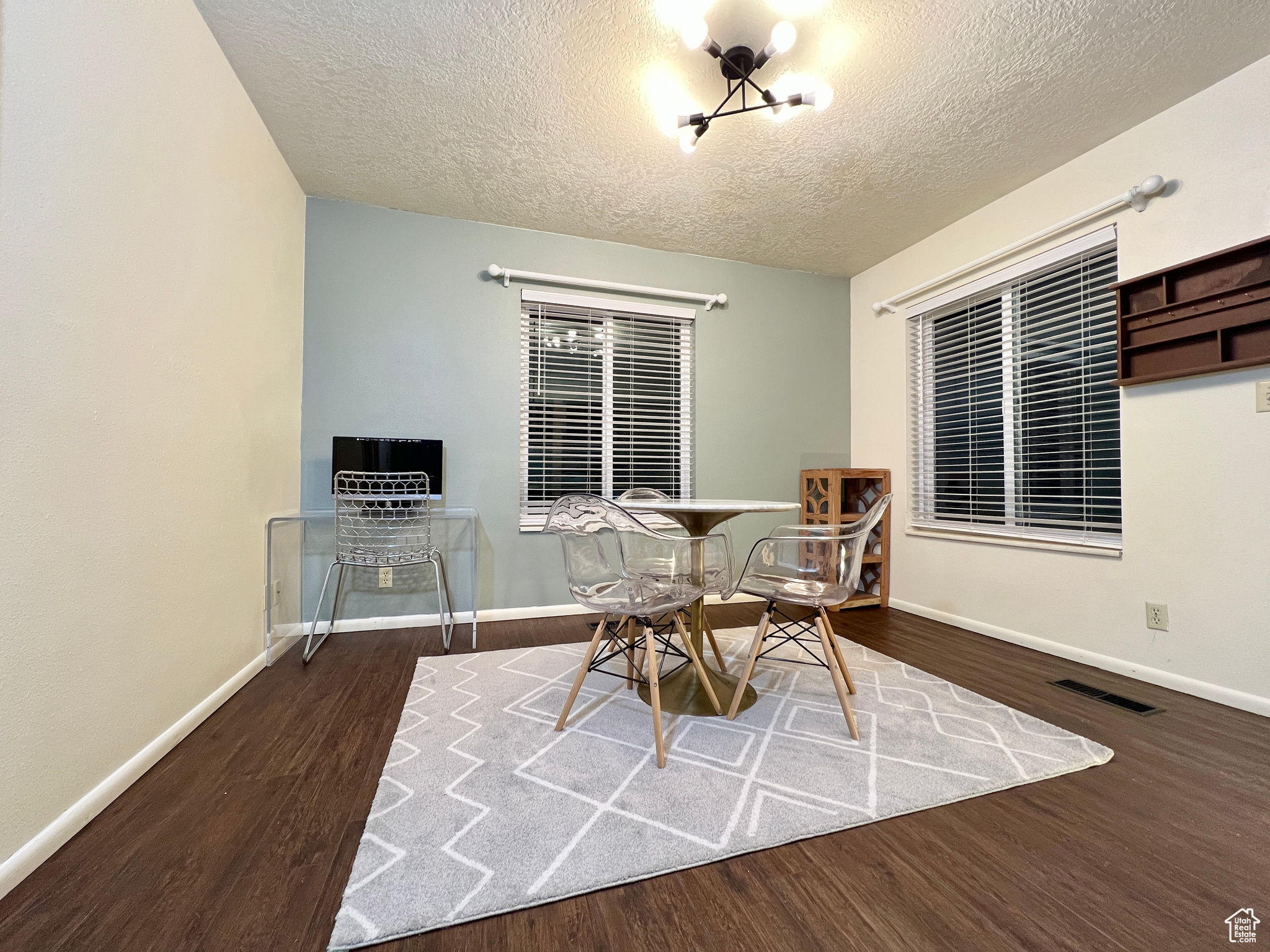 Dining area with a textured ceiling, wood finished floors, visible vents, and baseboards