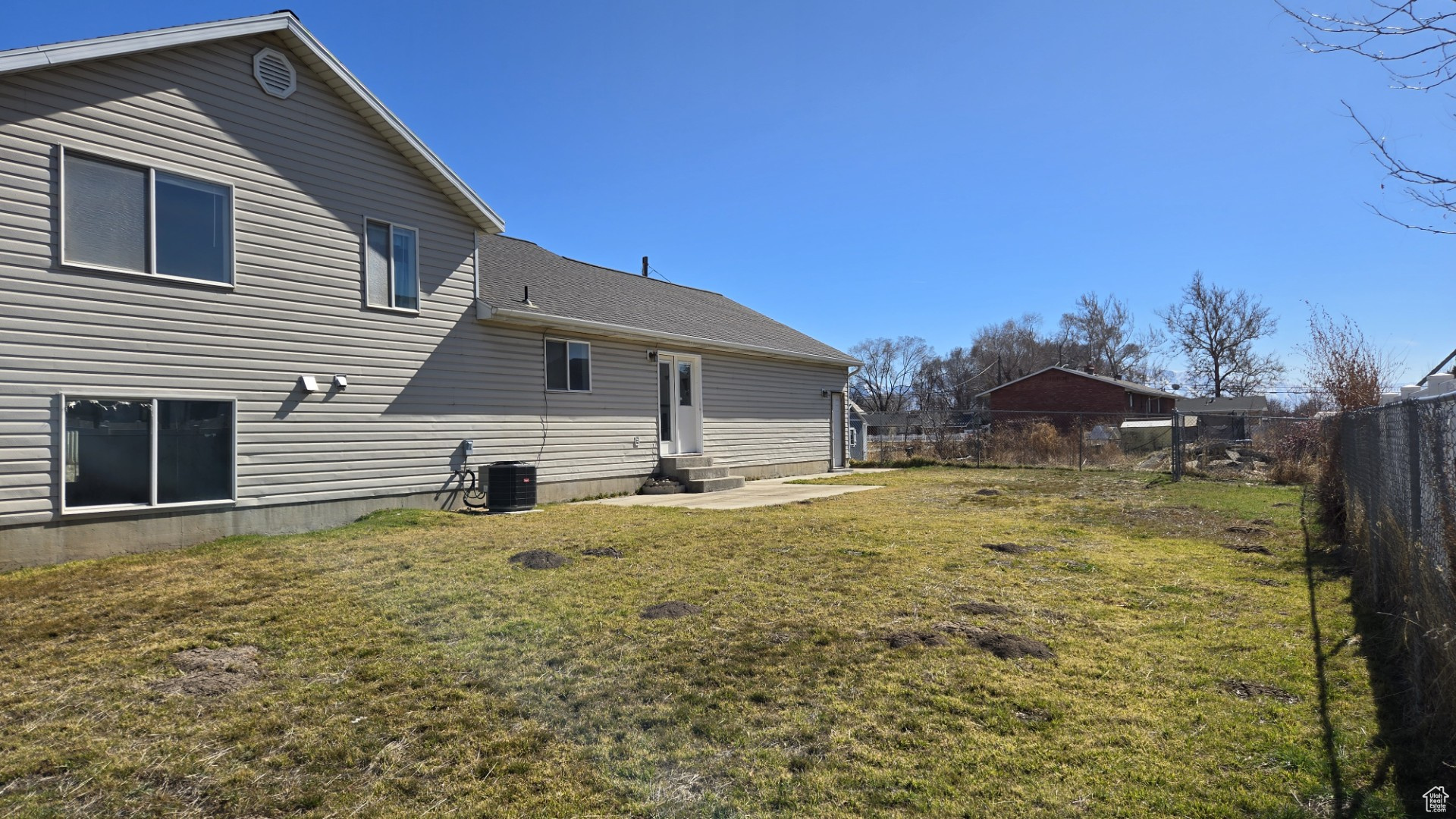 Back of house featuring a lawn, entry steps, a fenced backyard, roof with shingles, and central AC unit