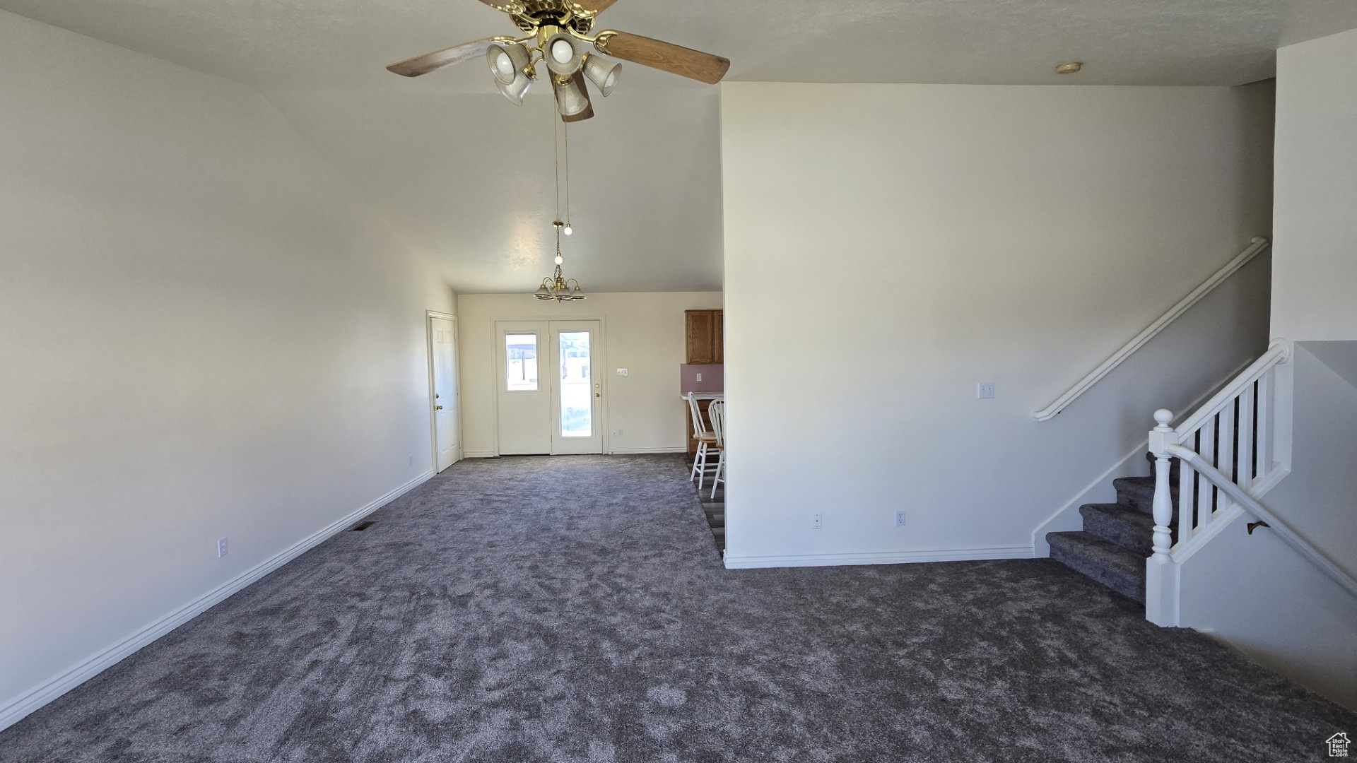 Unfurnished living room featuring stairs, a ceiling fan, baseboards, and carpet floors