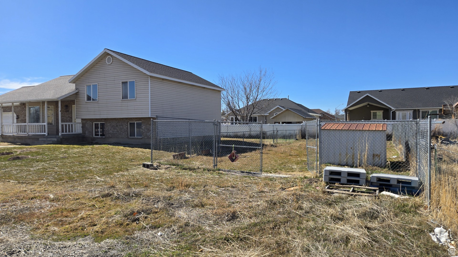 View of side of home featuring a yard, brick siding, and fence