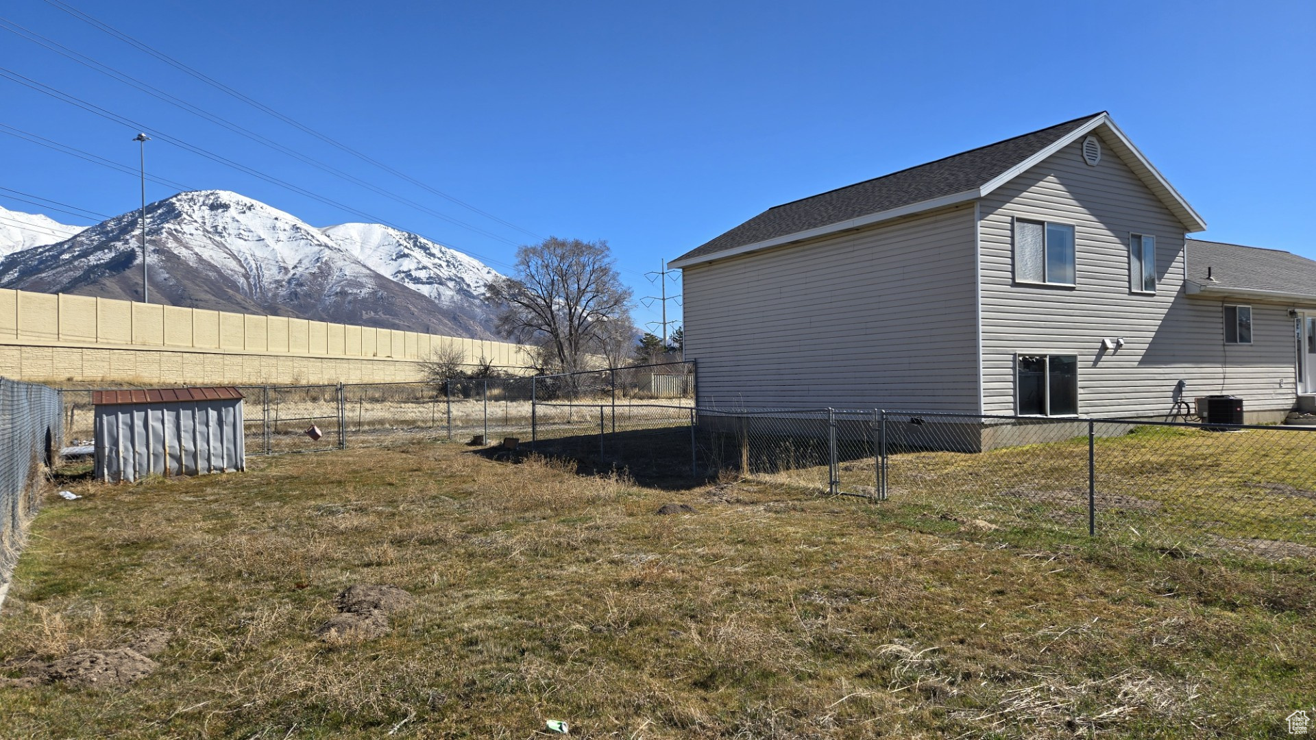 View of property exterior with central AC unit, a mountain view, a lawn, and a fenced backyard