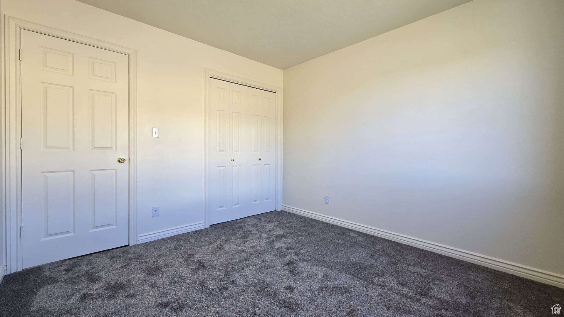 Unfurnished bedroom with a closet, baseboards, and dark carpet