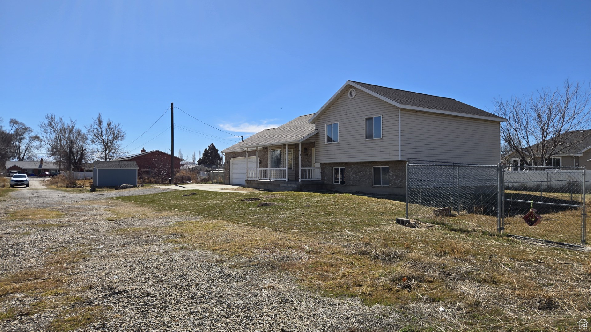 View of home's exterior featuring a garage, brick siding, driveway, and fence