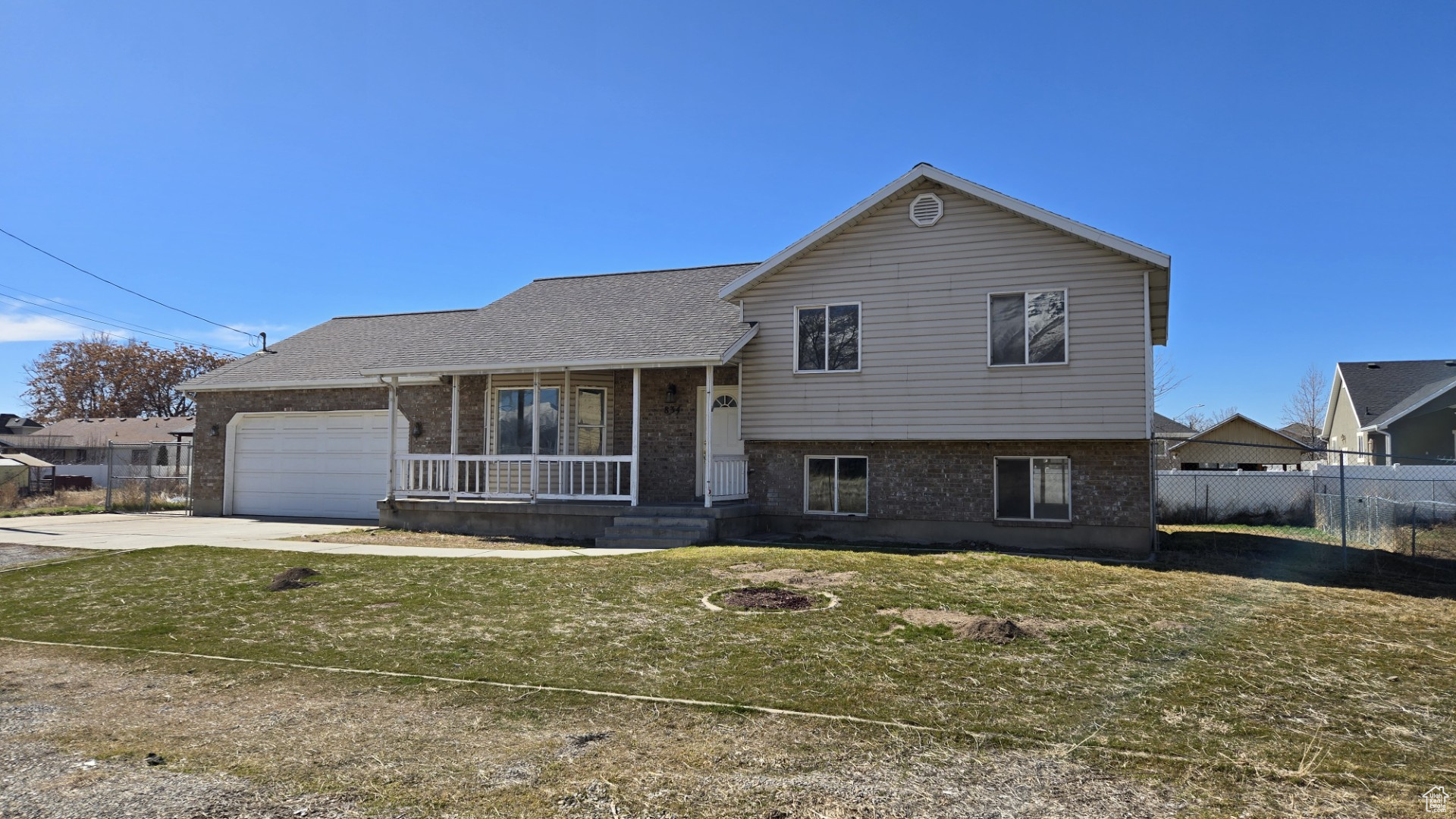 Split level home featuring brick siding, covered porch, concrete driveway, and fence