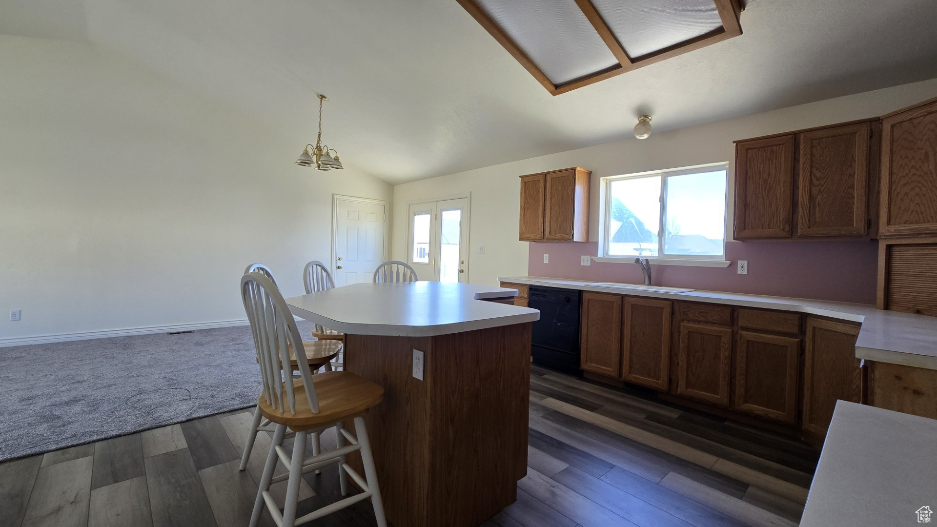 Kitchen featuring a sink, a kitchen island, dishwasher, and light countertops