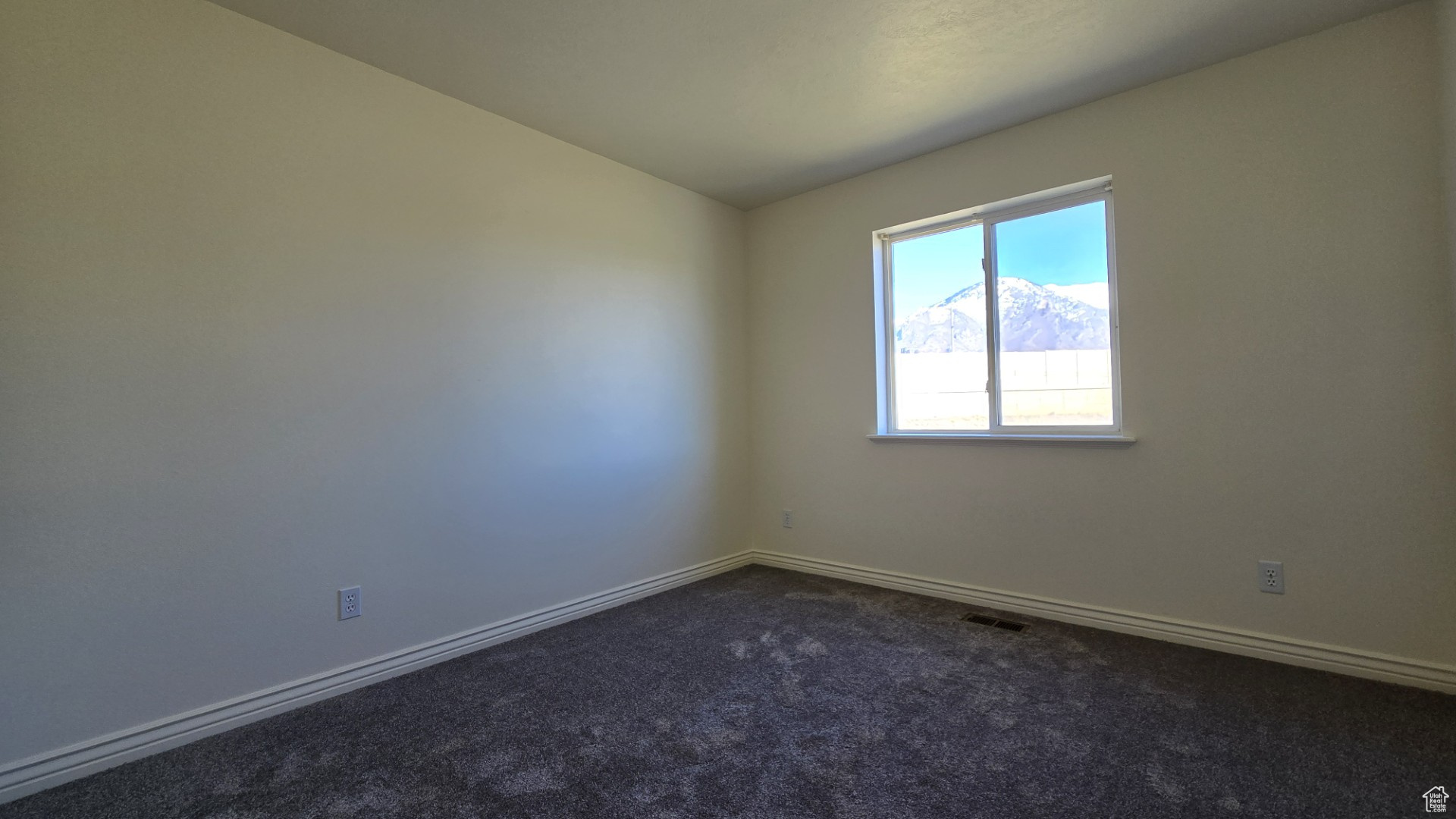 Empty room with visible vents, baseboards, and dark colored carpet