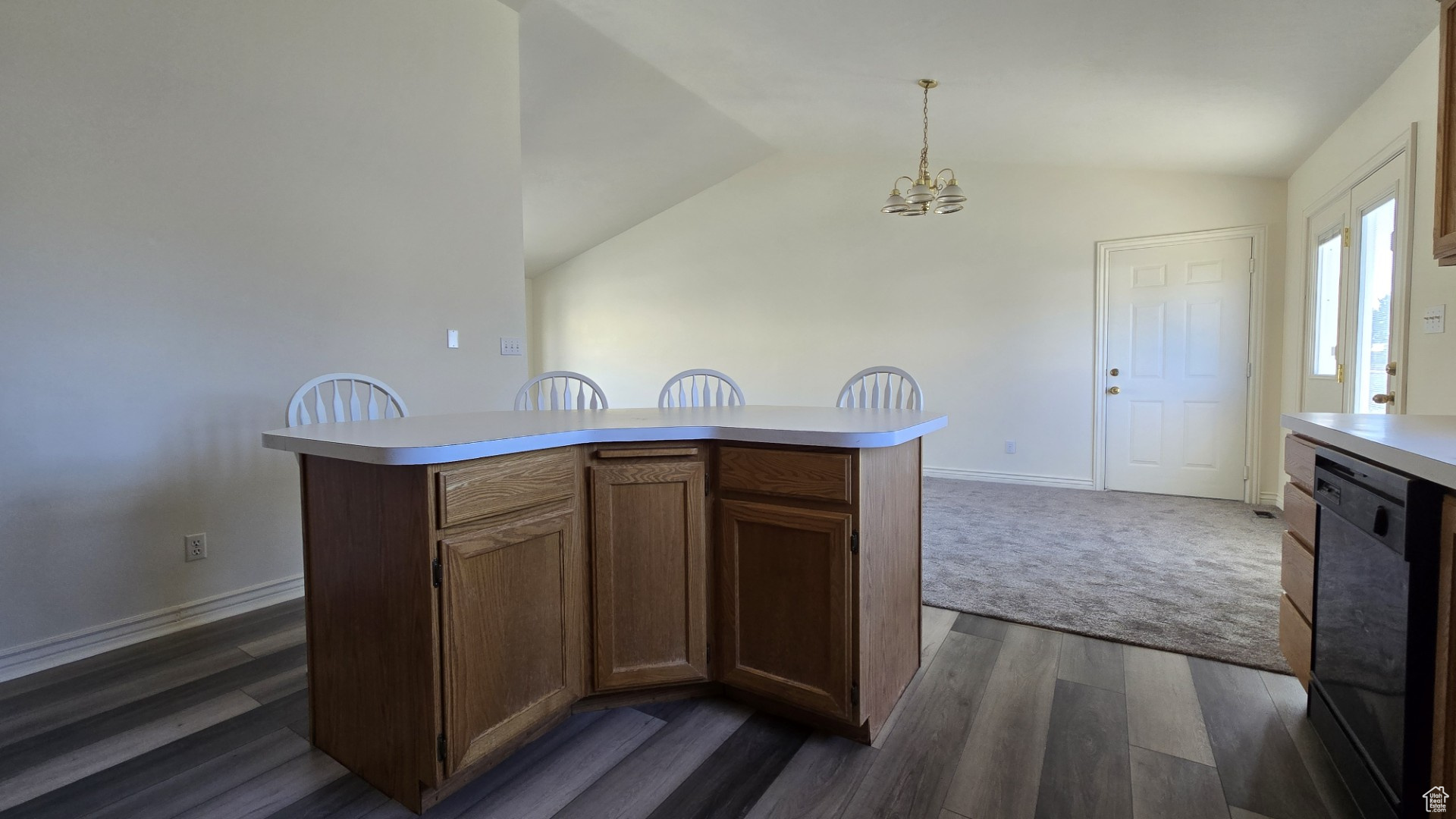 Kitchen featuring a notable chandelier, light countertops, black dishwasher, and vaulted ceiling