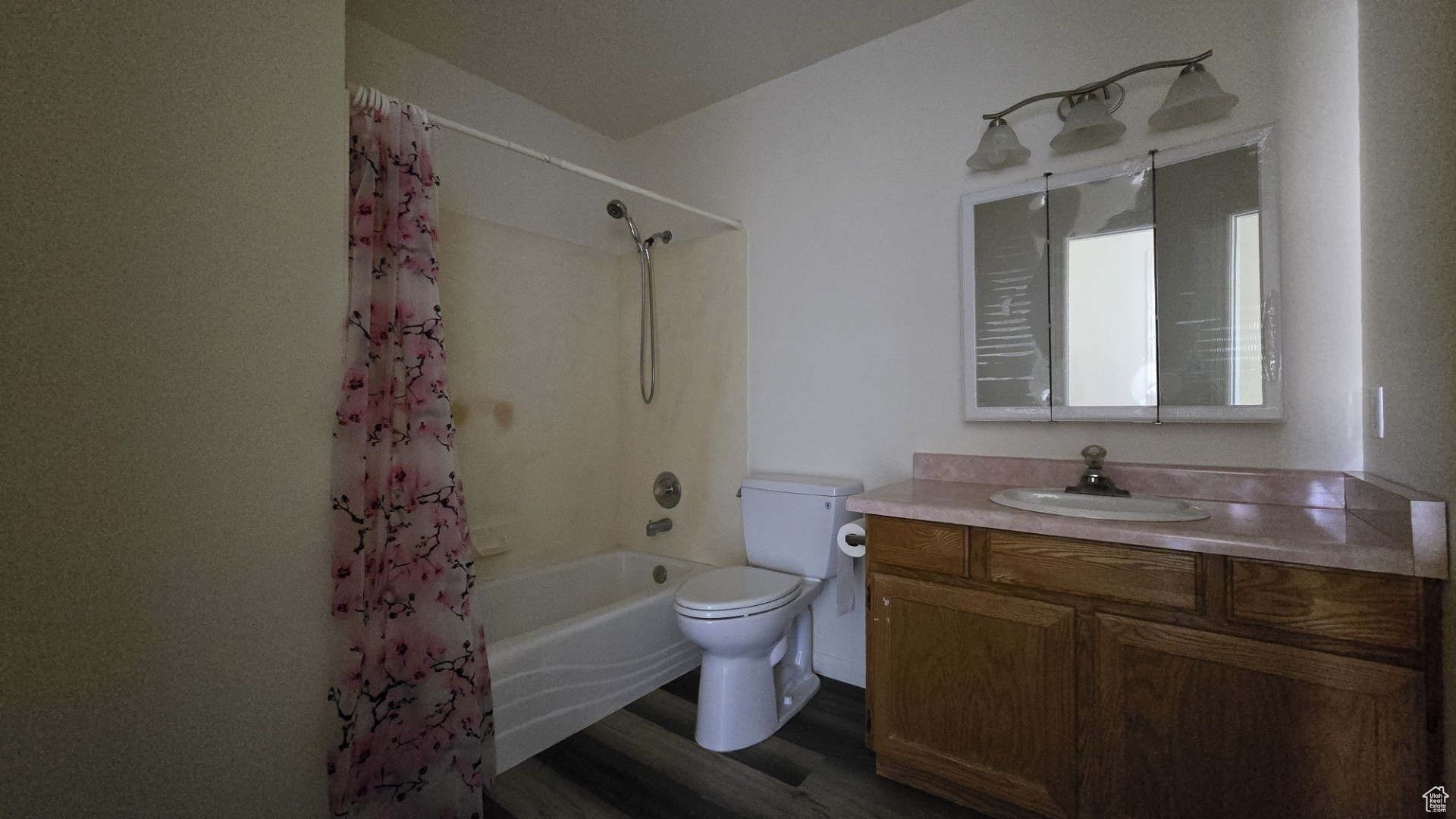 Full bathroom featuring shower / bath combo with shower curtain, toilet, wood finished floors, and vanity