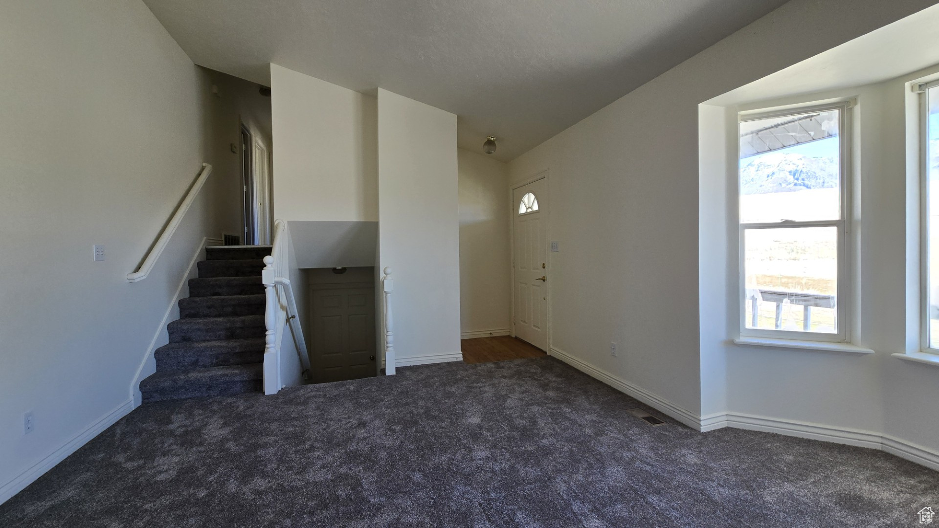 Interior space with stairs, carpet flooring, and baseboards