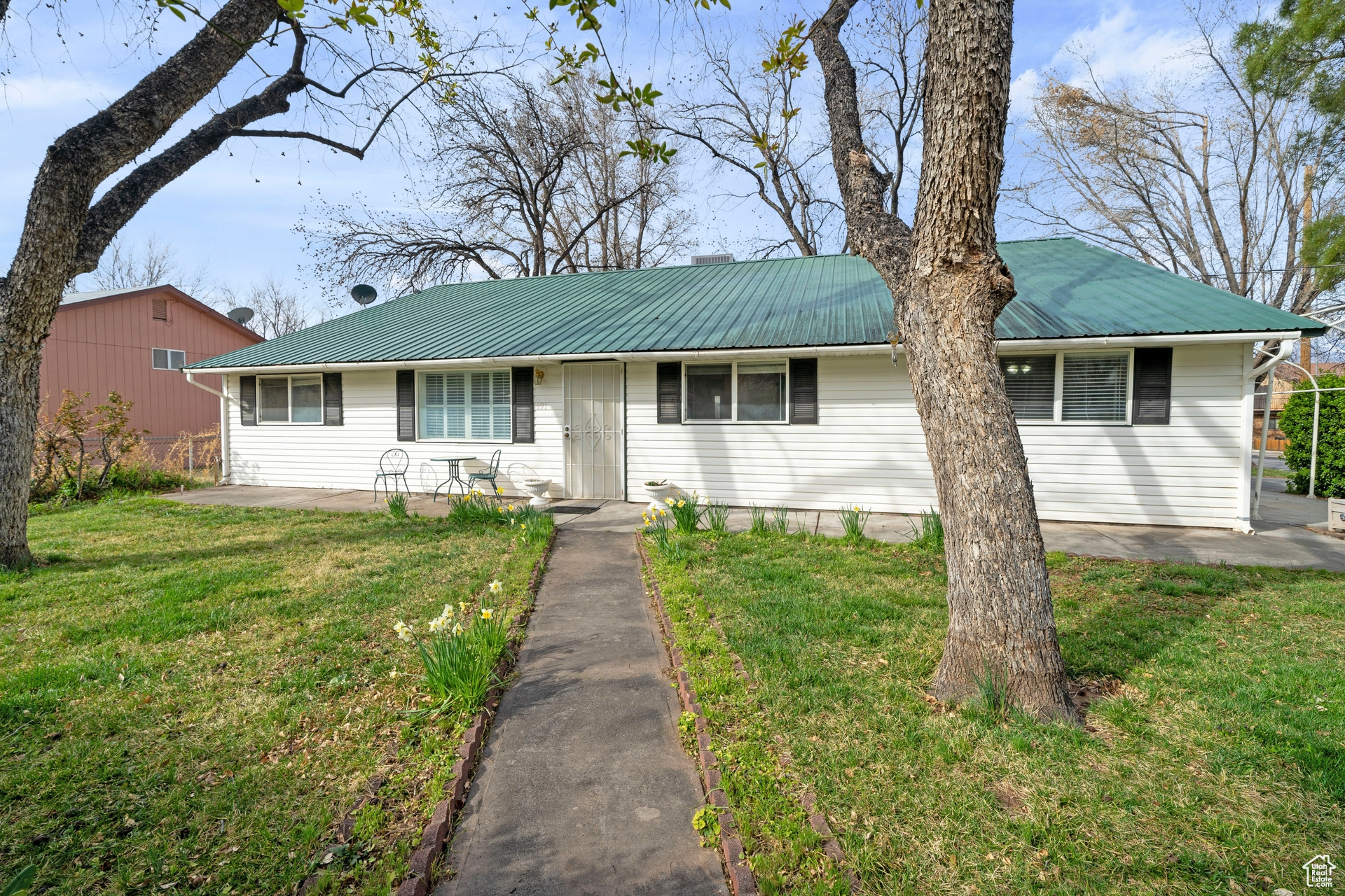 Ranch/Rambler-style home front entrance with mature trees and landscaping