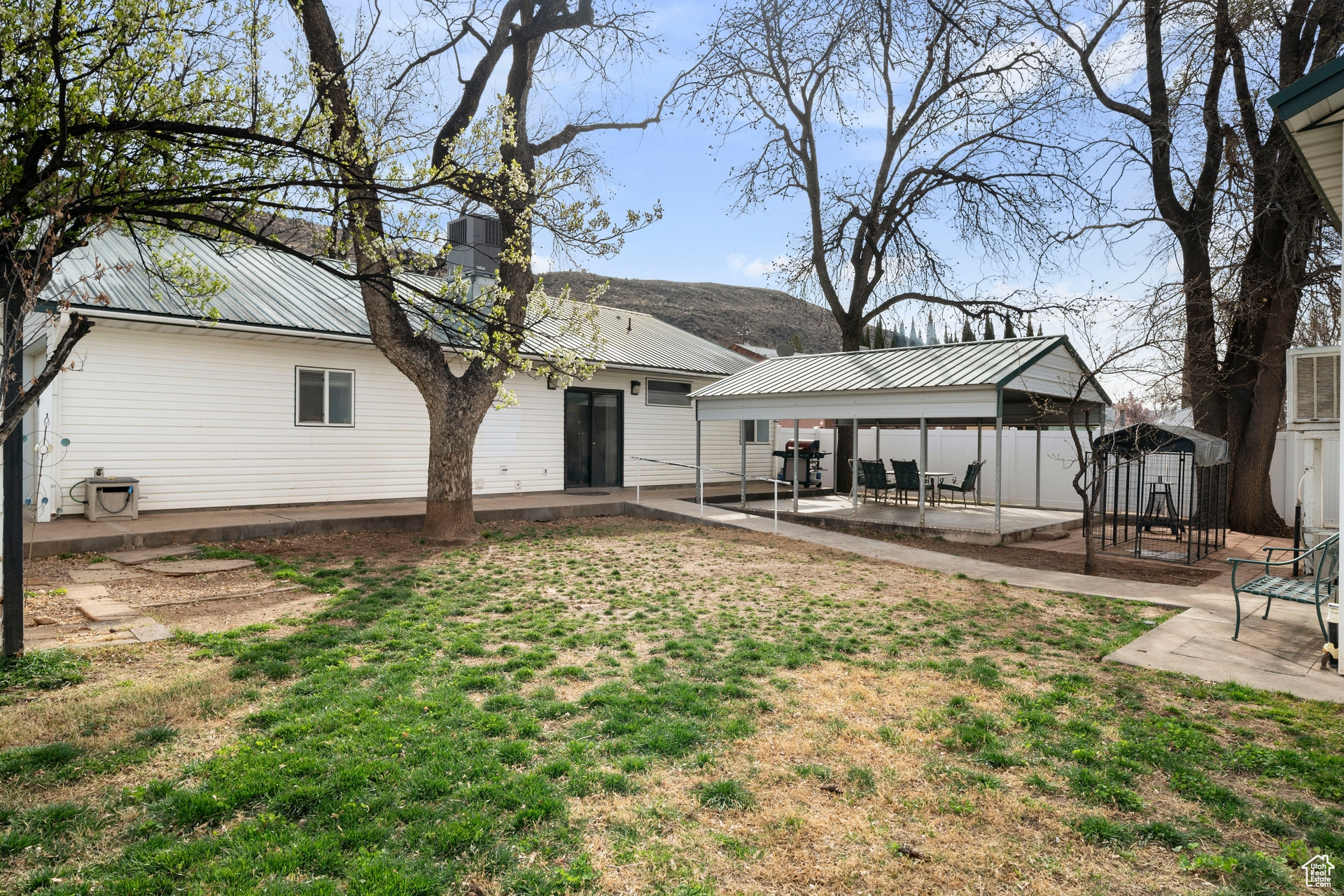 Rear view of property with a covered patio and mature trees