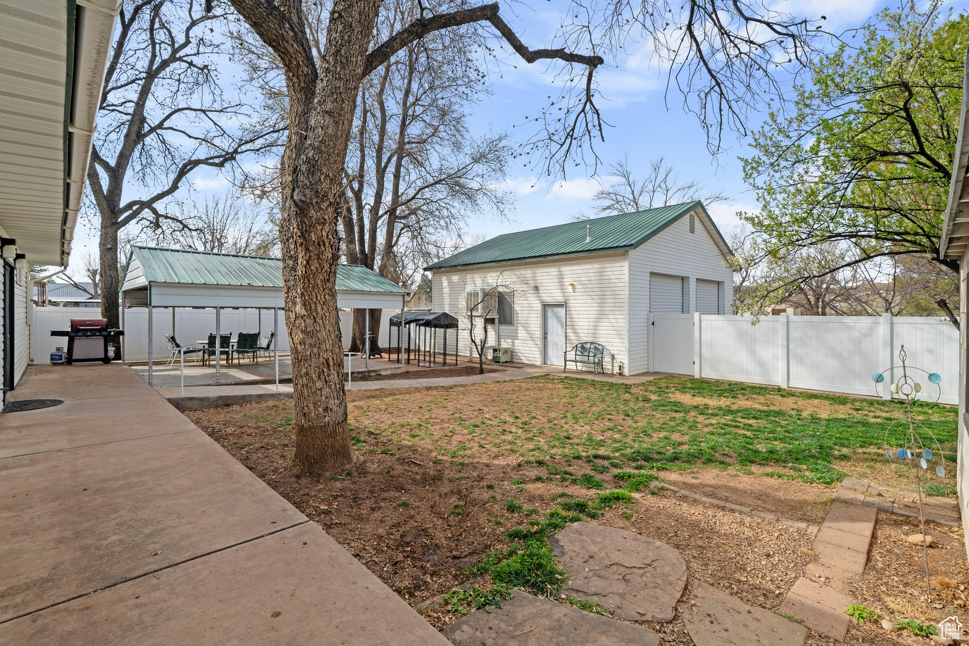 View of backyard with large, detached garage, a covered patio, and fully fenced