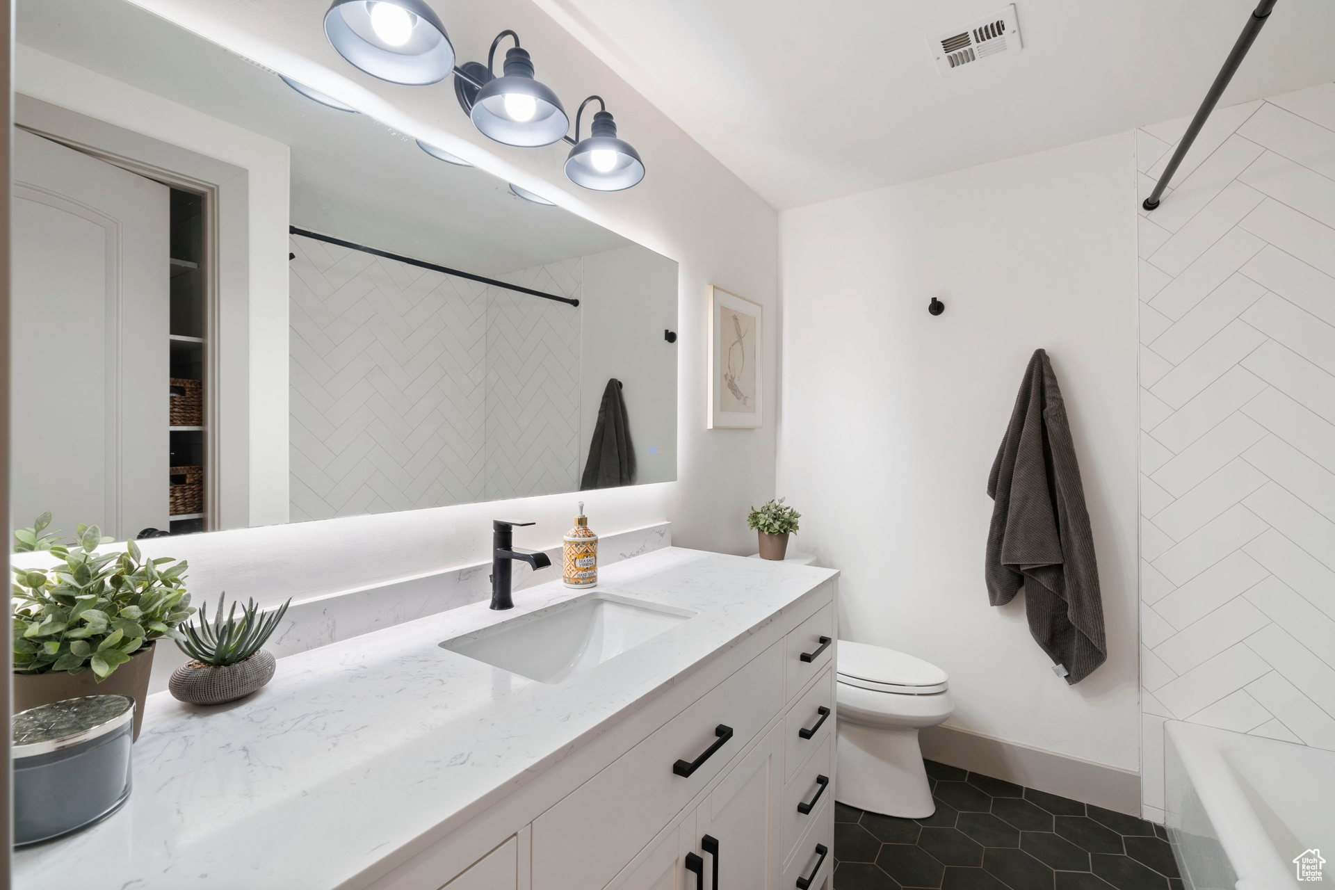 Full updated bath with toilet, shower / bathing tub combination, tile patterned floors, and vanity