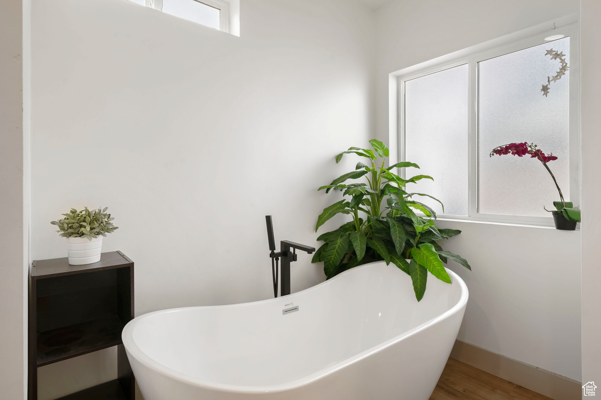 Primary bath featuring a freestanding bath, and wood style floors, double vanity and luxurious shower