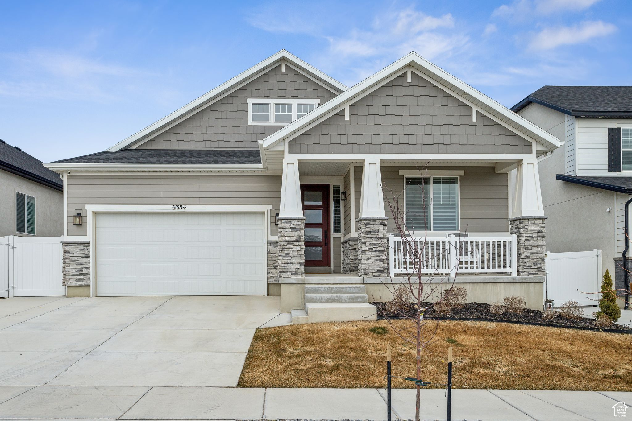 Craftsman-style home featuring stone siding, a porch, fence, concrete driveway, and a garage