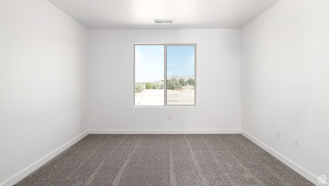 Carpeted spare room with visible vents and baseboards