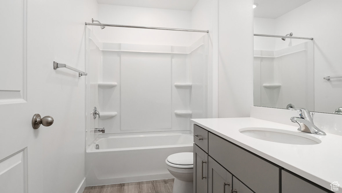 Bathroom with vanity, toilet, wood finished floors, and bathtub / shower combination