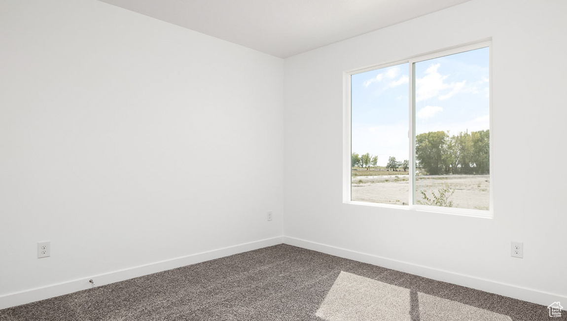 Unfurnished room with dark carpet and baseboards