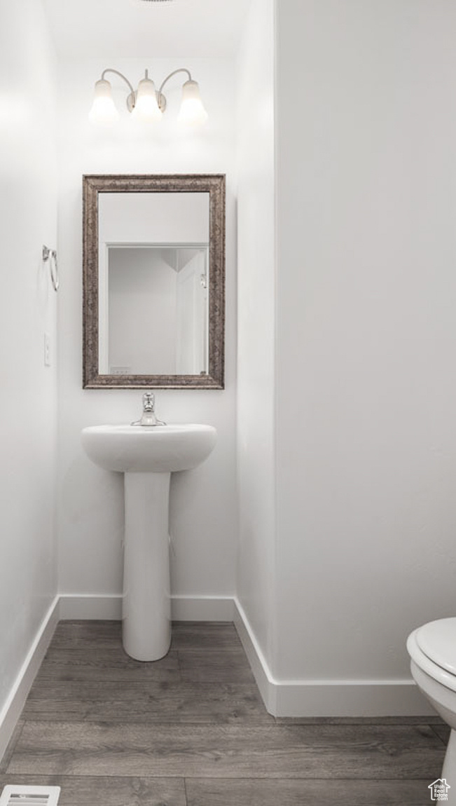 Half bath with toilet, baseboards, and wood finished floors