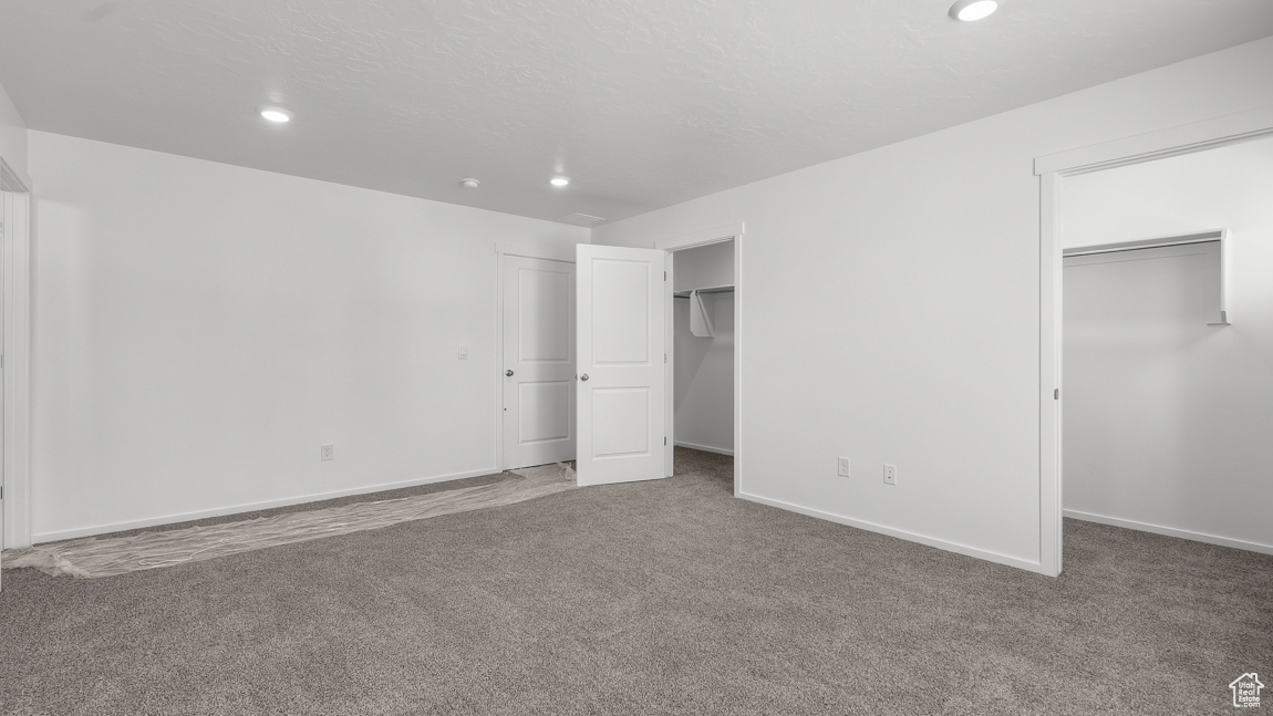 Unfurnished bedroom with recessed lighting, two closets, and carpet floors