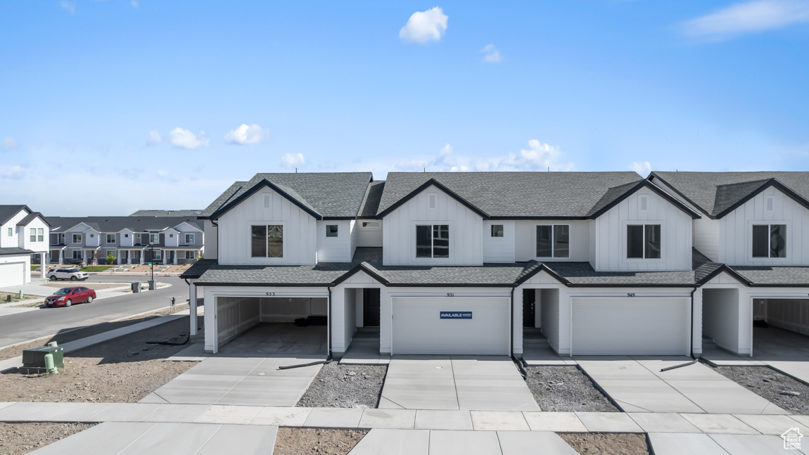 View of front facade with an attached garage, board and batten siding, a residential view, and roof with shingles