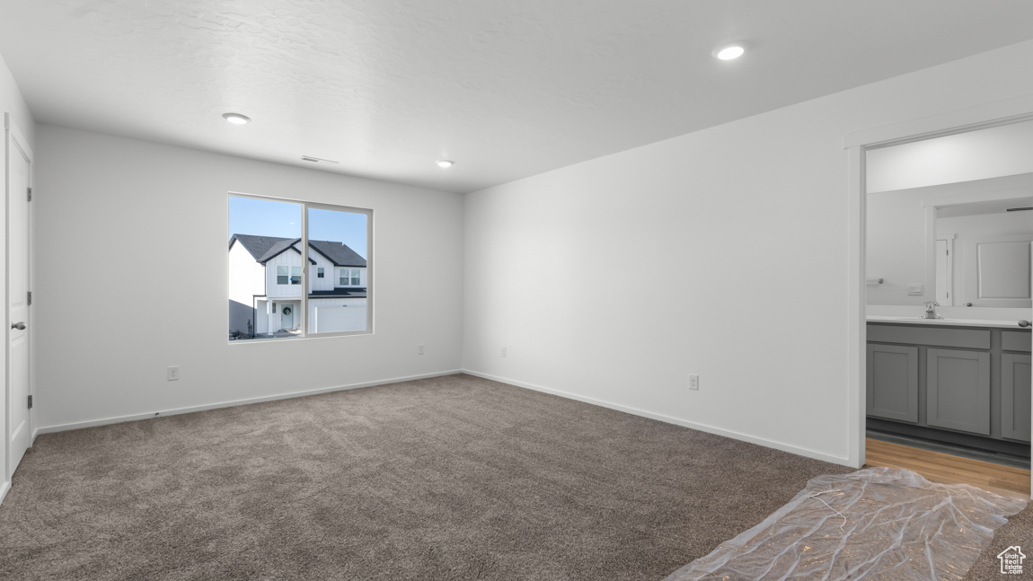 Interior space featuring visible vents, a sink, recessed lighting, carpet, and baseboards