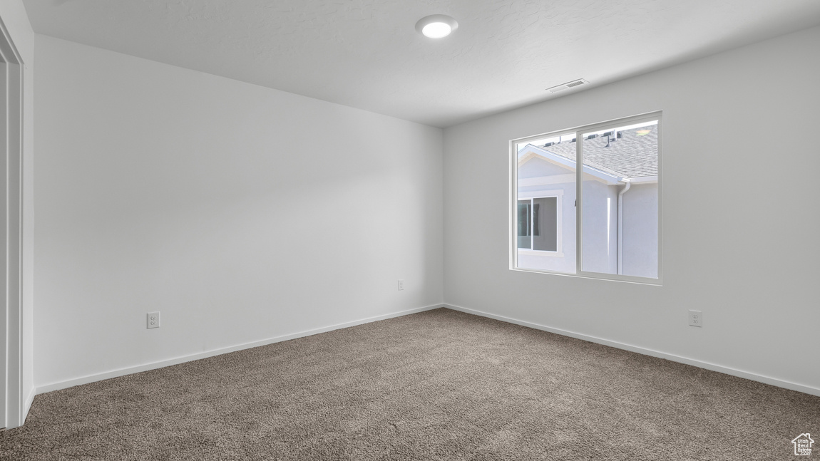 Carpeted empty room with visible vents and baseboards