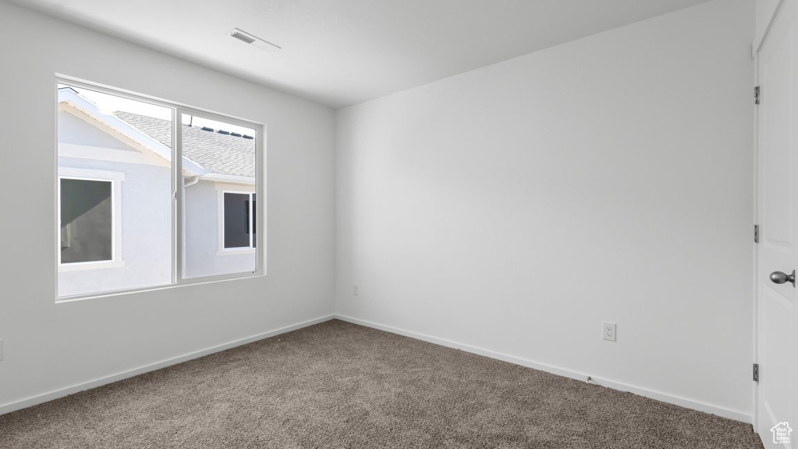 Carpeted spare room with visible vents and baseboards