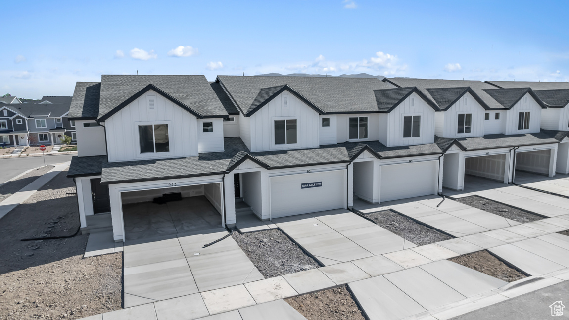 View of front of home with driveway, a residential view, board and batten siding, a shingled roof, and a garage