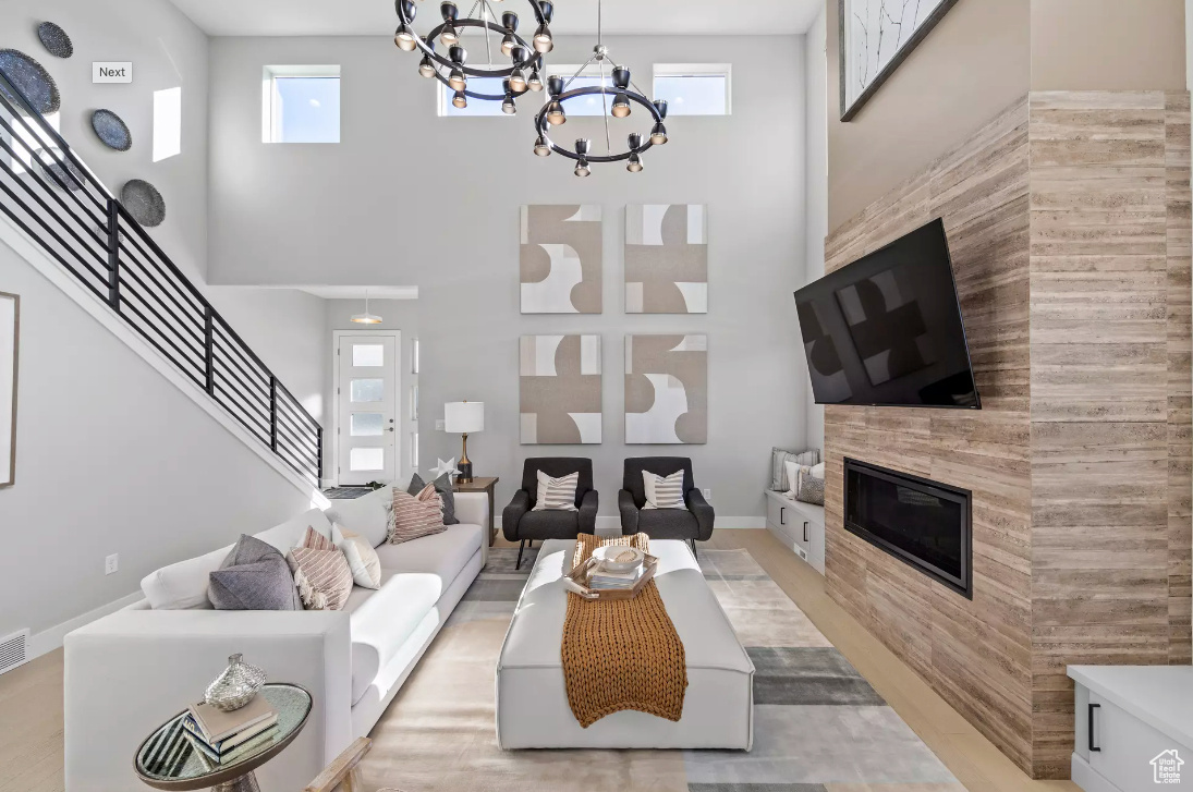 Living room featuring a notable chandelier, a high ceiling, a fireplace, and stairs