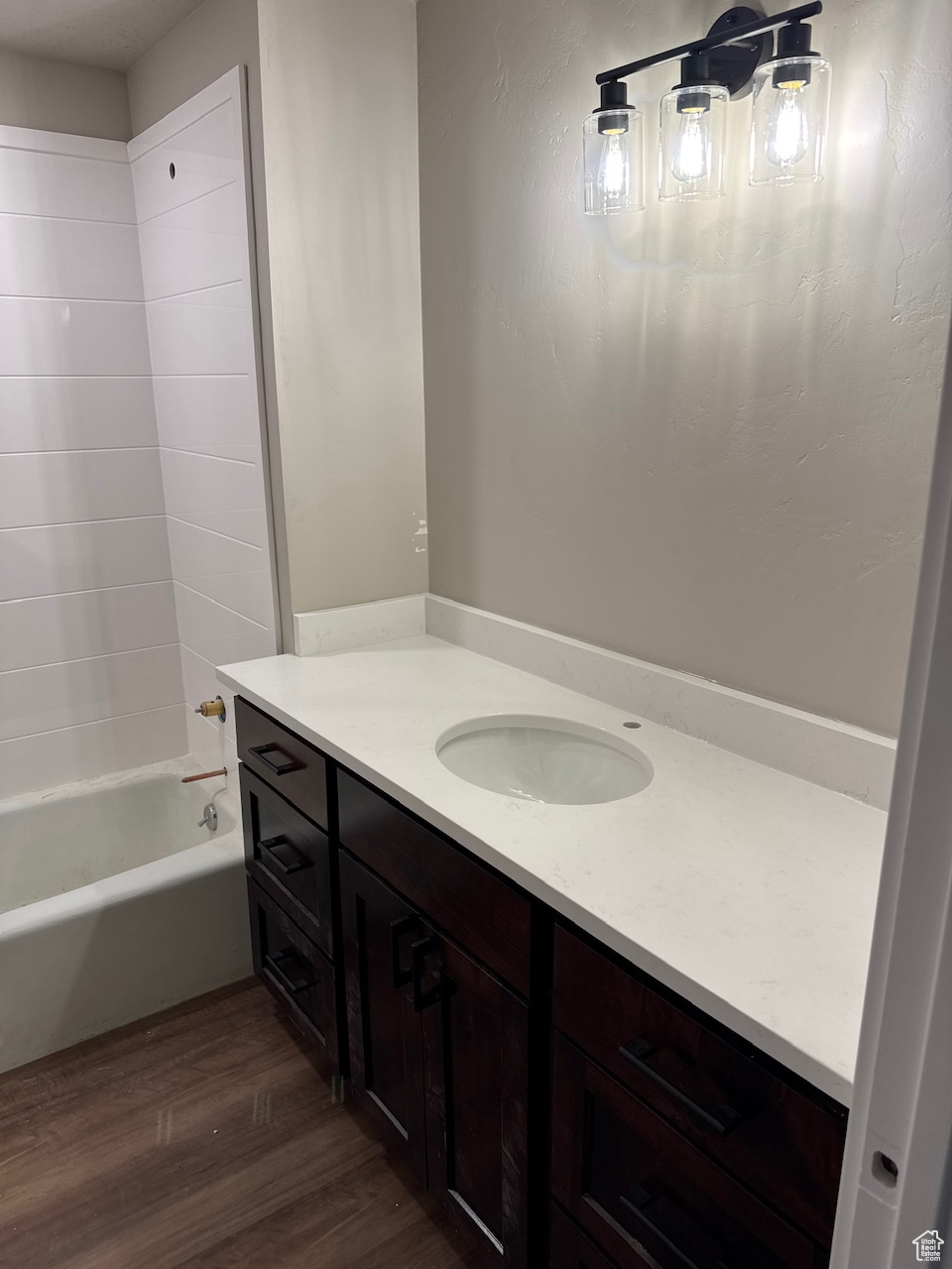 Bathroom with shower / washtub combination, wood finished floors, and vanity