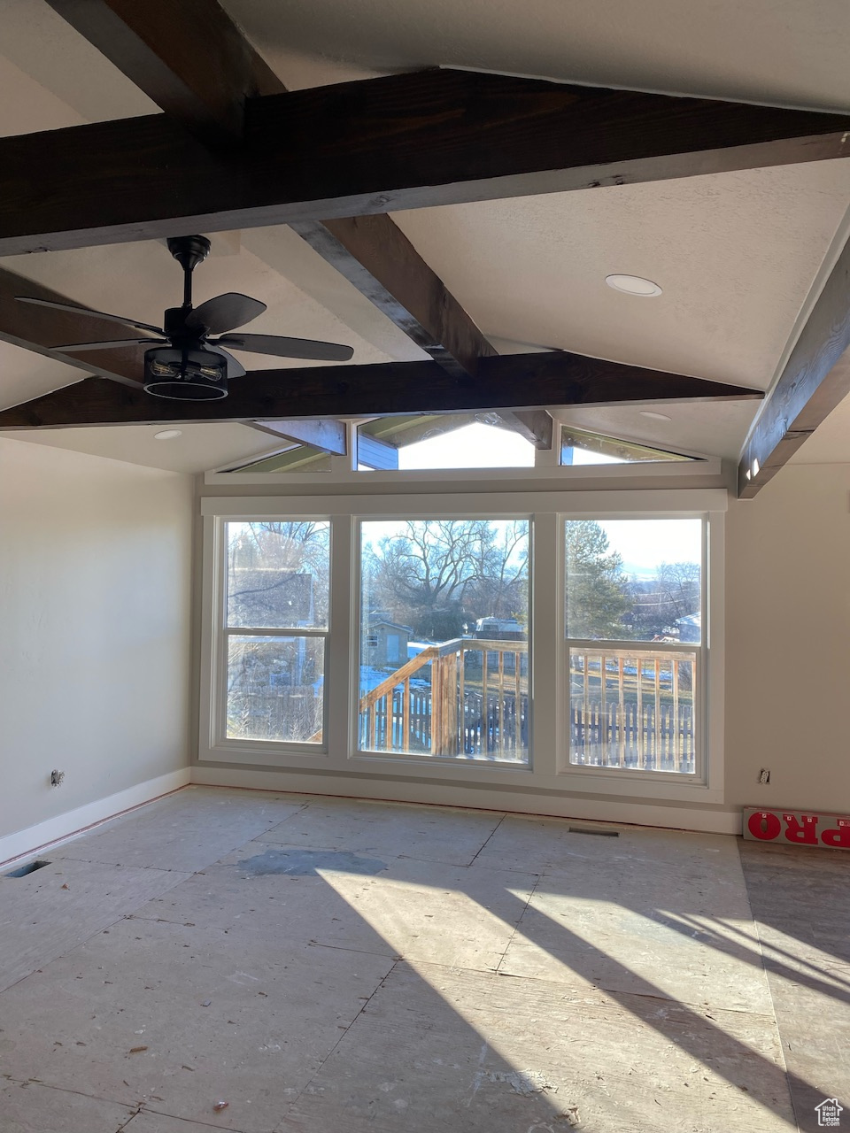 Unfurnished room with lofted ceiling with beams, plenty of natural light, and ceiling fan