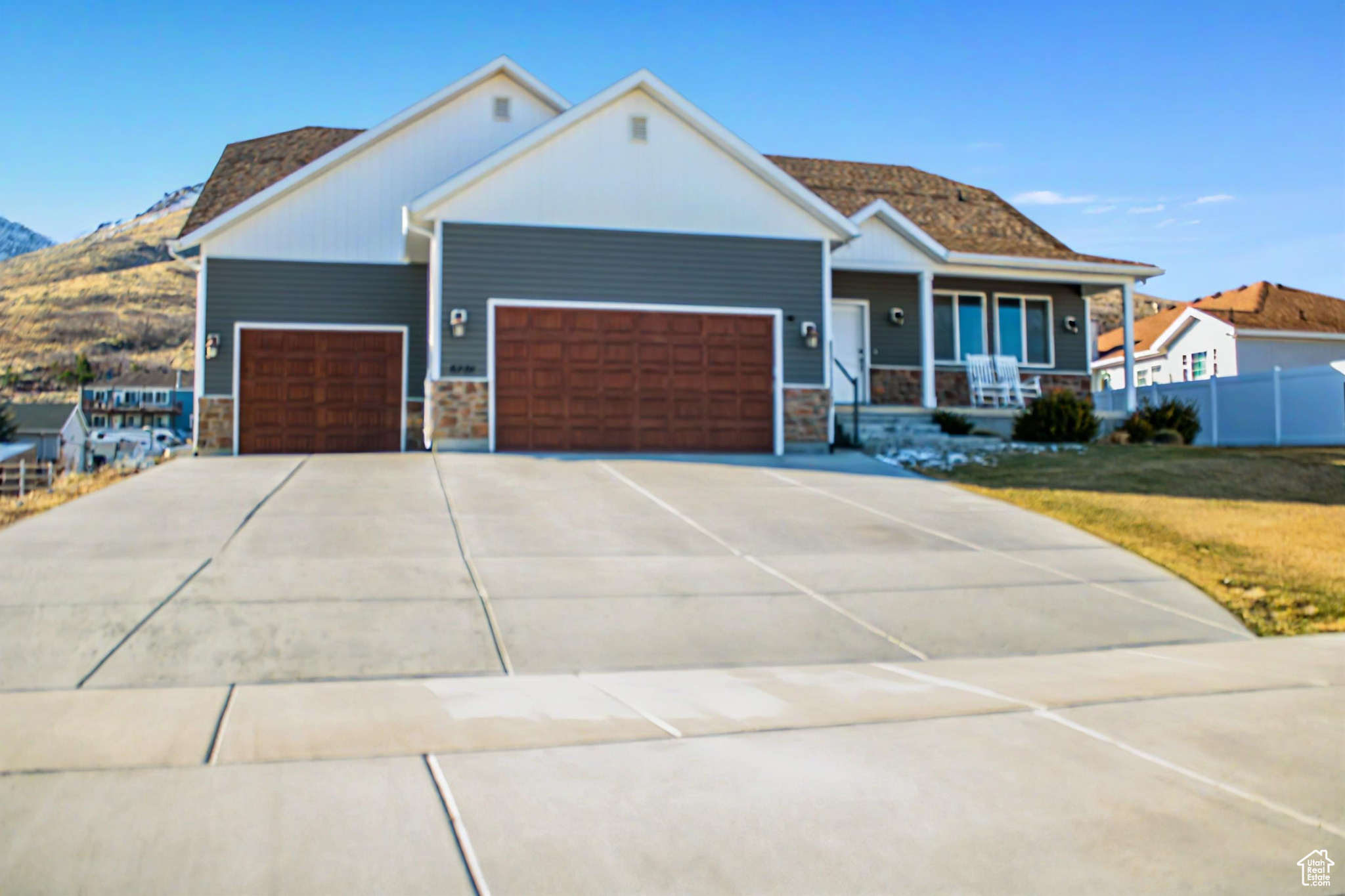 View of front of home with stone siding, covered porch, concrete driveway, and a garage