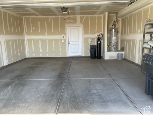 Garage featuring strapped water heater and a garage door opener