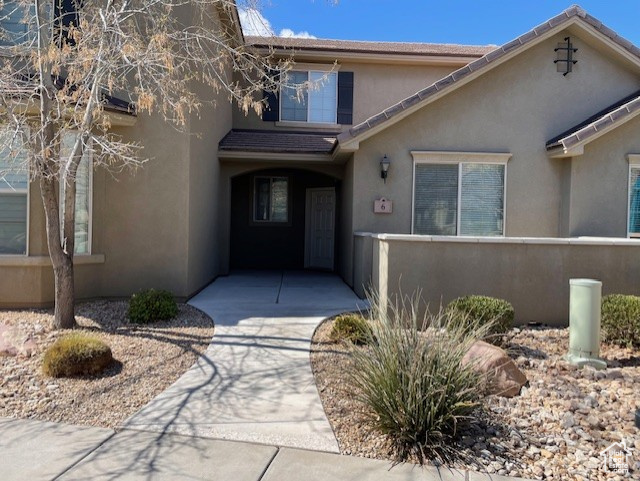 View of exterior entry featuring concrete sidewalk, fence, and patio