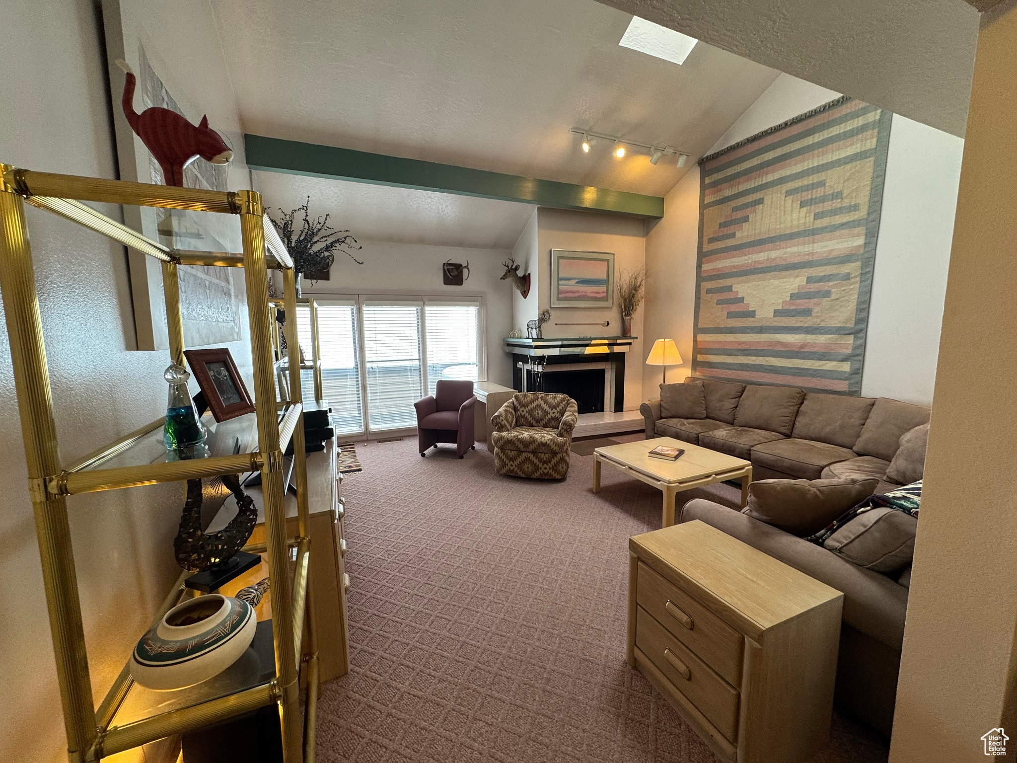 Living room with lofted ceiling, a fireplace with raised hearth, and dark carpet