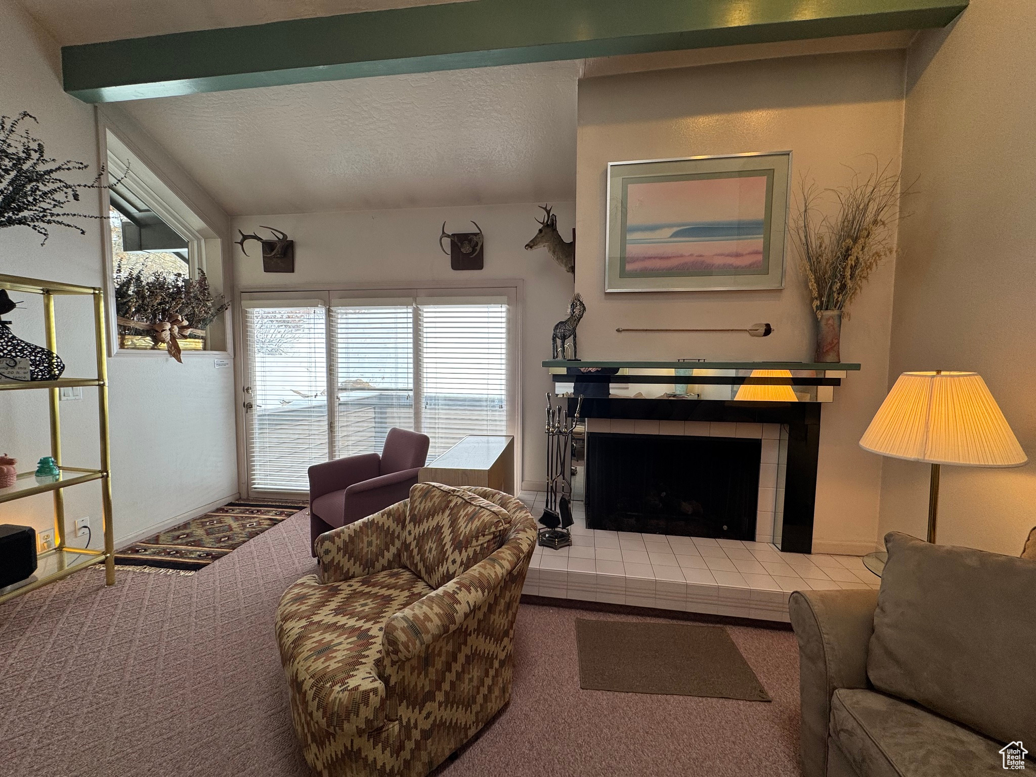 Living area with a textured ceiling, beam ceiling, carpet, and a tile fireplace