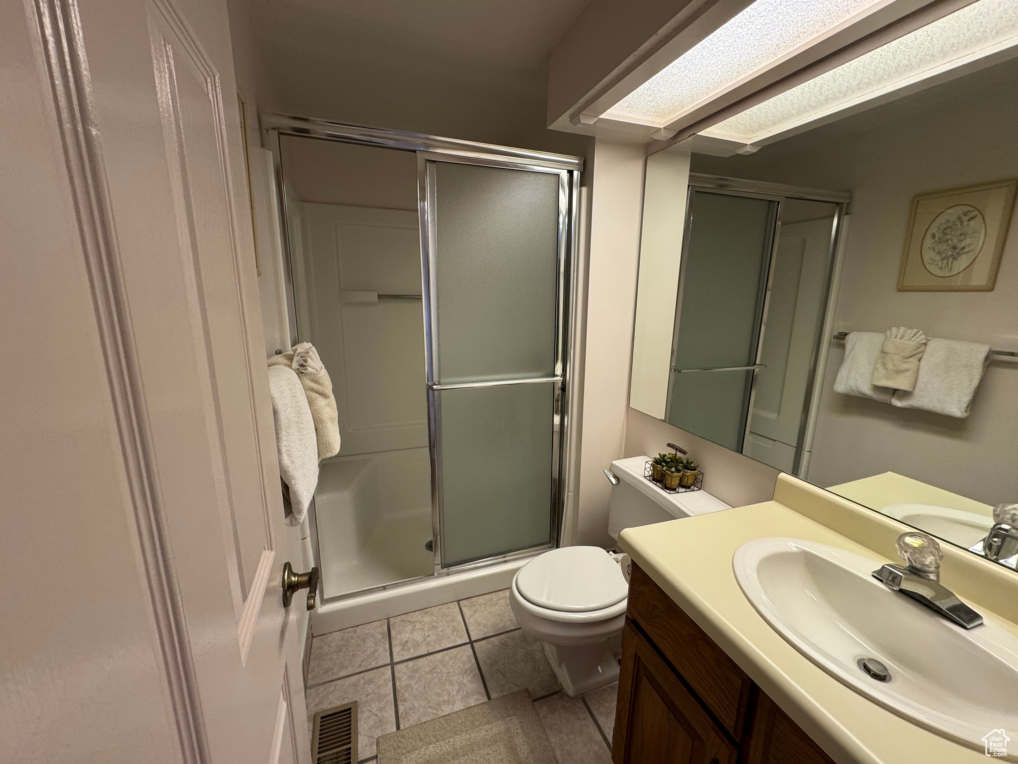 Bathroom featuring vanity, visible vents, a stall shower, tile patterned flooring, and toilet