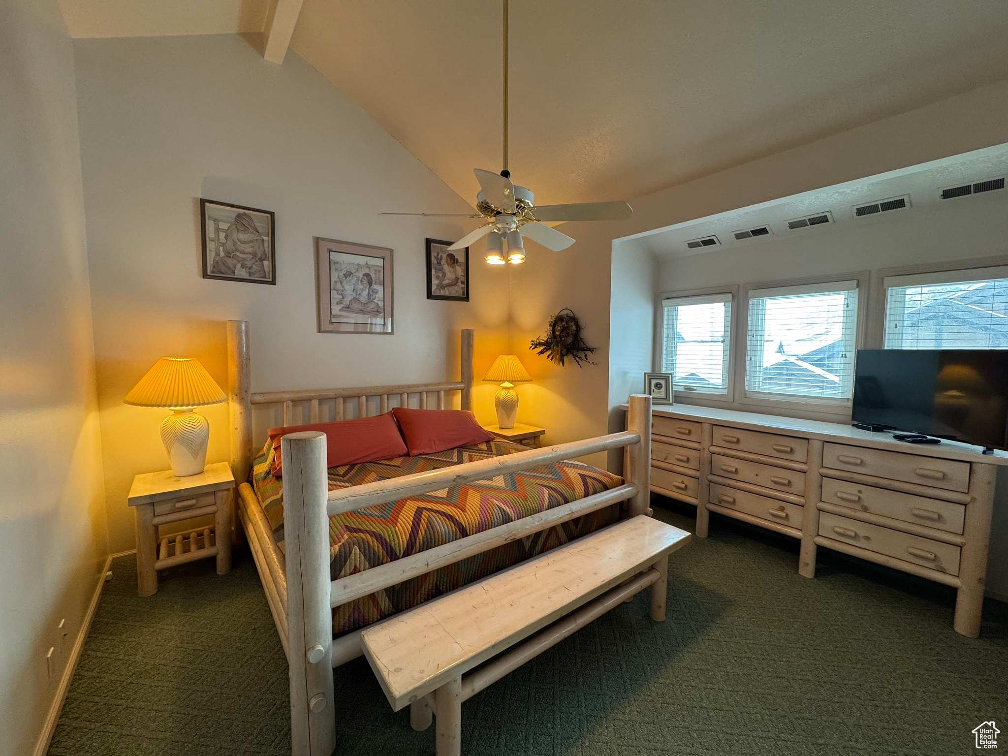 Bedroom with visible vents, dark carpet, vaulted ceiling with beams, and baseboards