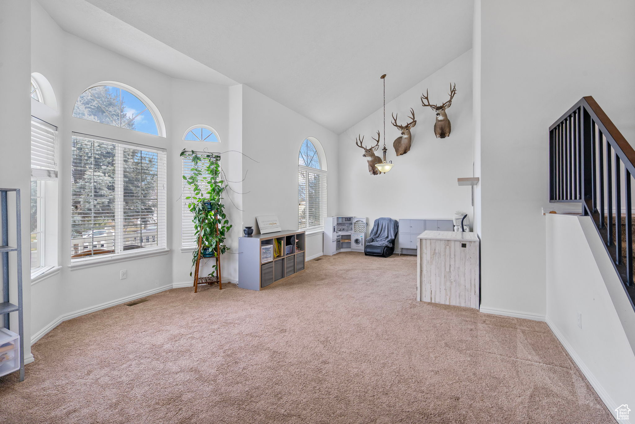 Interior space with baseboards, high vaulted ceiling, and carpet flooring