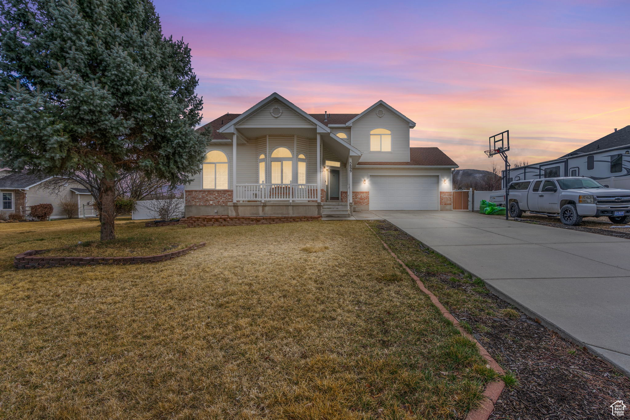 View of front of home with driveway, brick siding, a porch, and a front yard