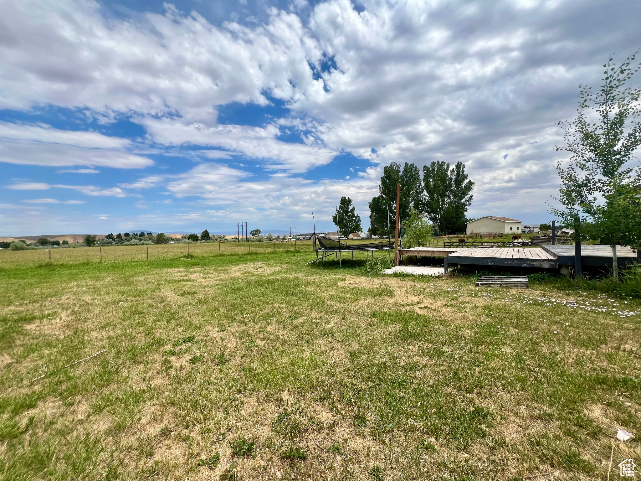 View of yard with a trampoline, a rural view, and fence