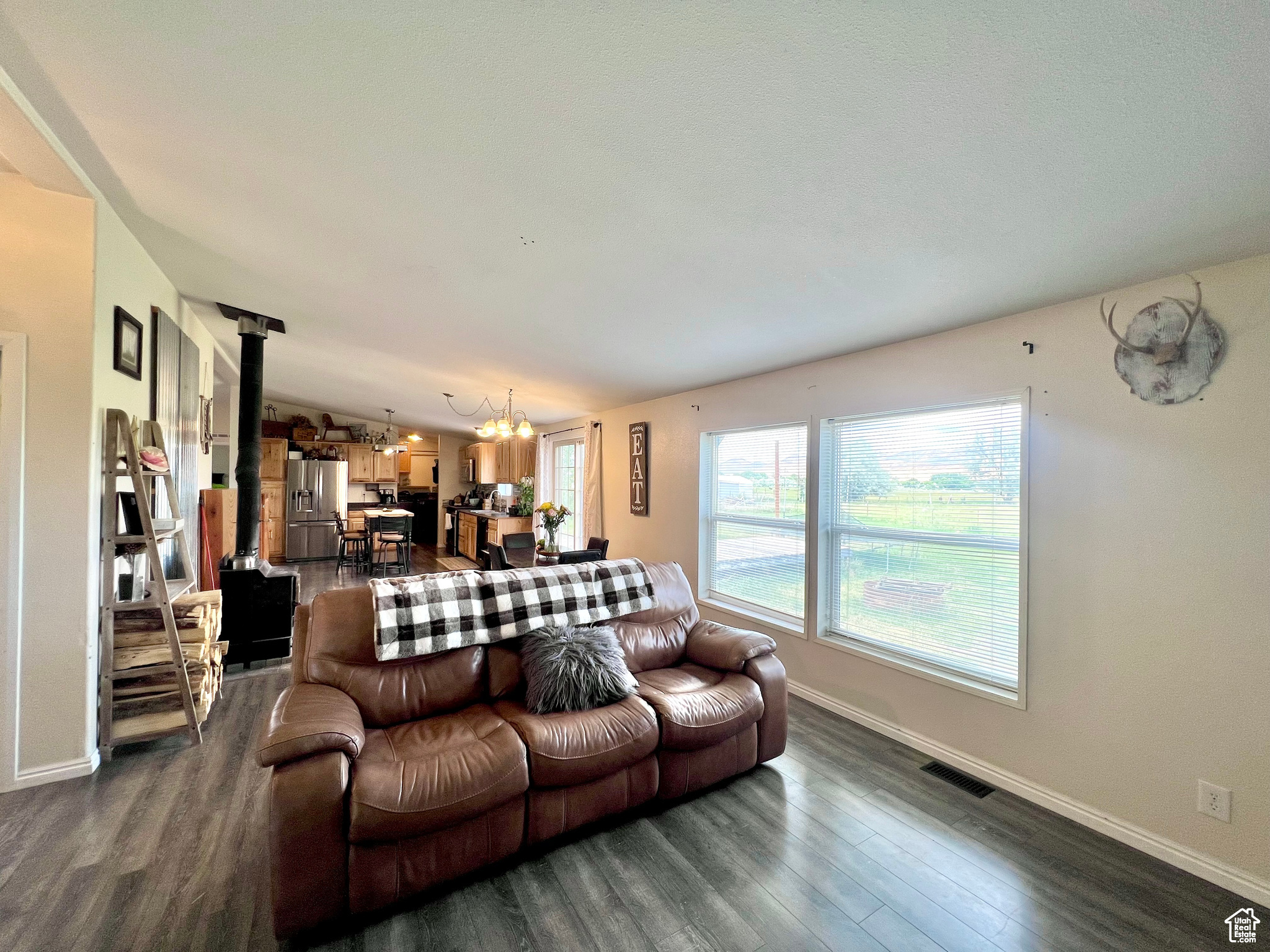 Living area featuring visible vents, dark wood-style flooring, a chandelier, and a wood stove